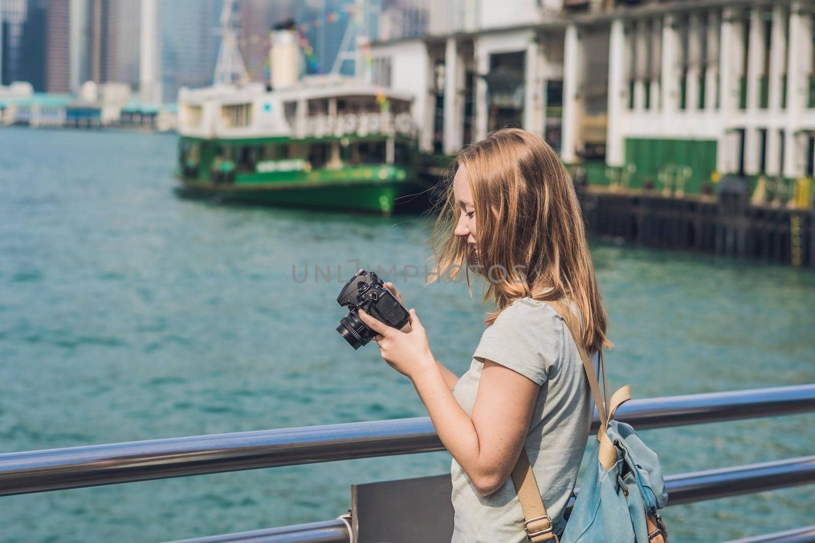 Young woman taking photos of victoria harbor in Hong Kong, China by galitskaya