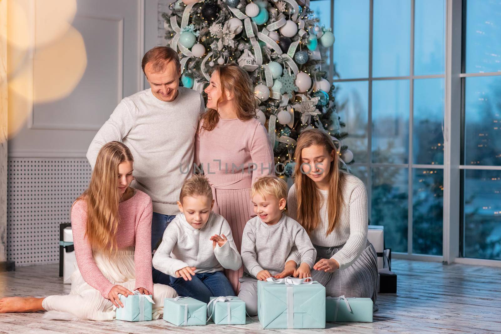 Big Happy family with many kids having fun and opening presents under the Christmas tree. Christmas family eve, christmas mood concept