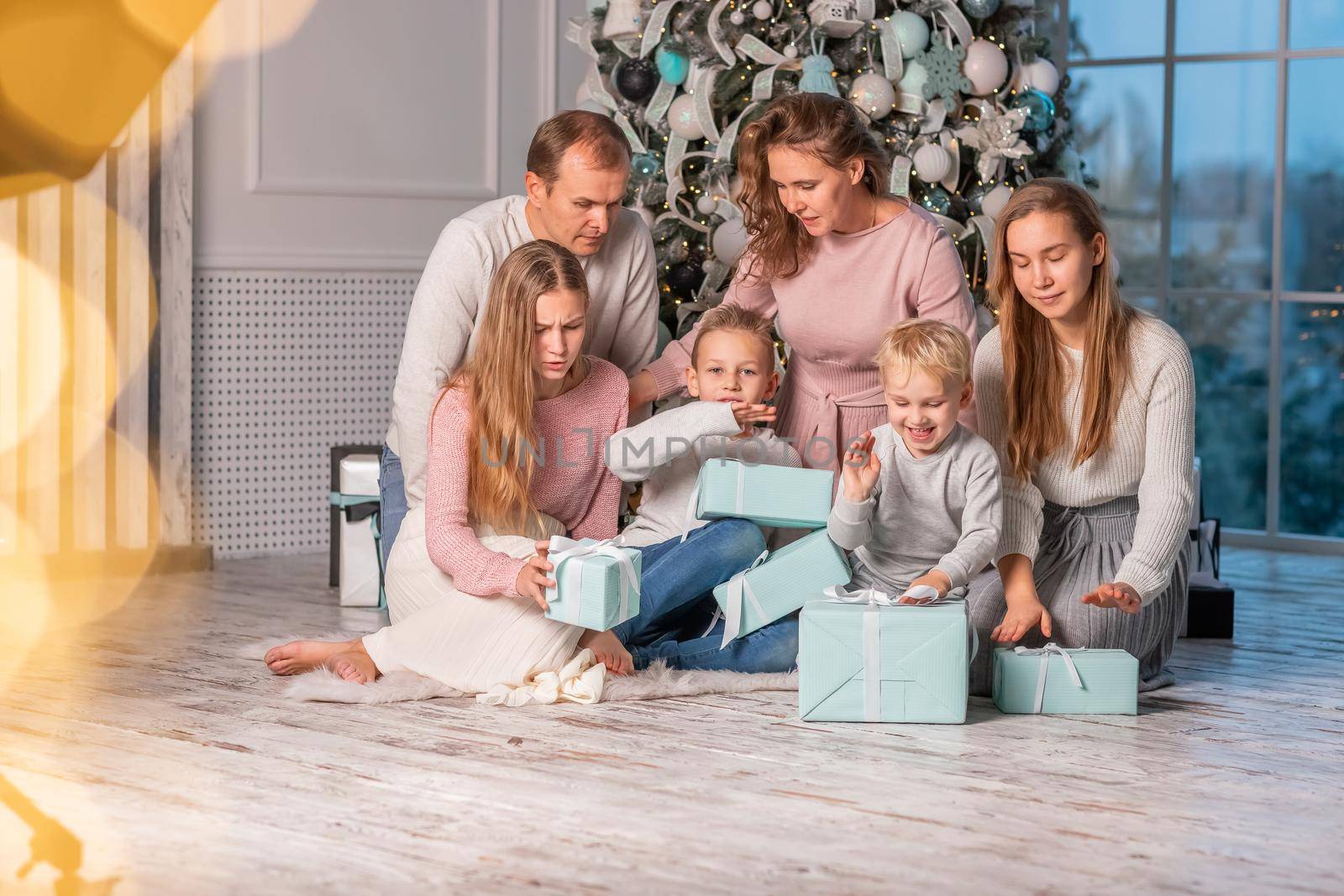 Big Happy family with many kids having fun and opening presents under the Christmas tree. Christmas family eve, christmas mood concept
