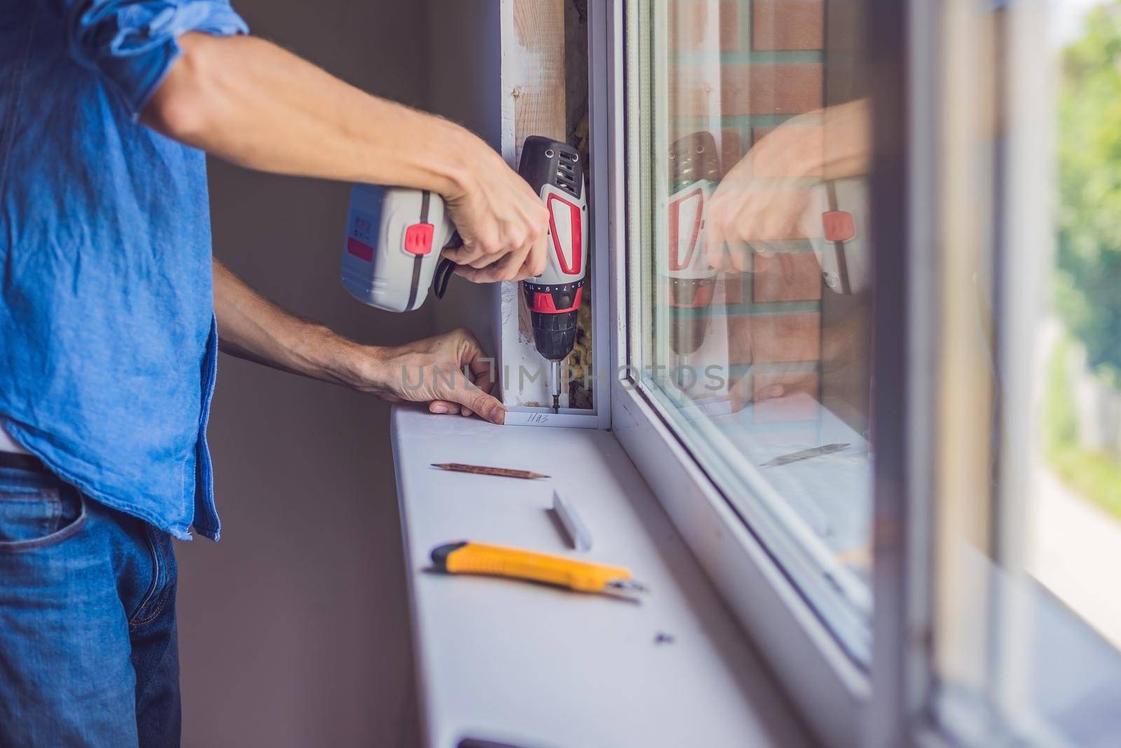 Man in a blue shirt does window installation.