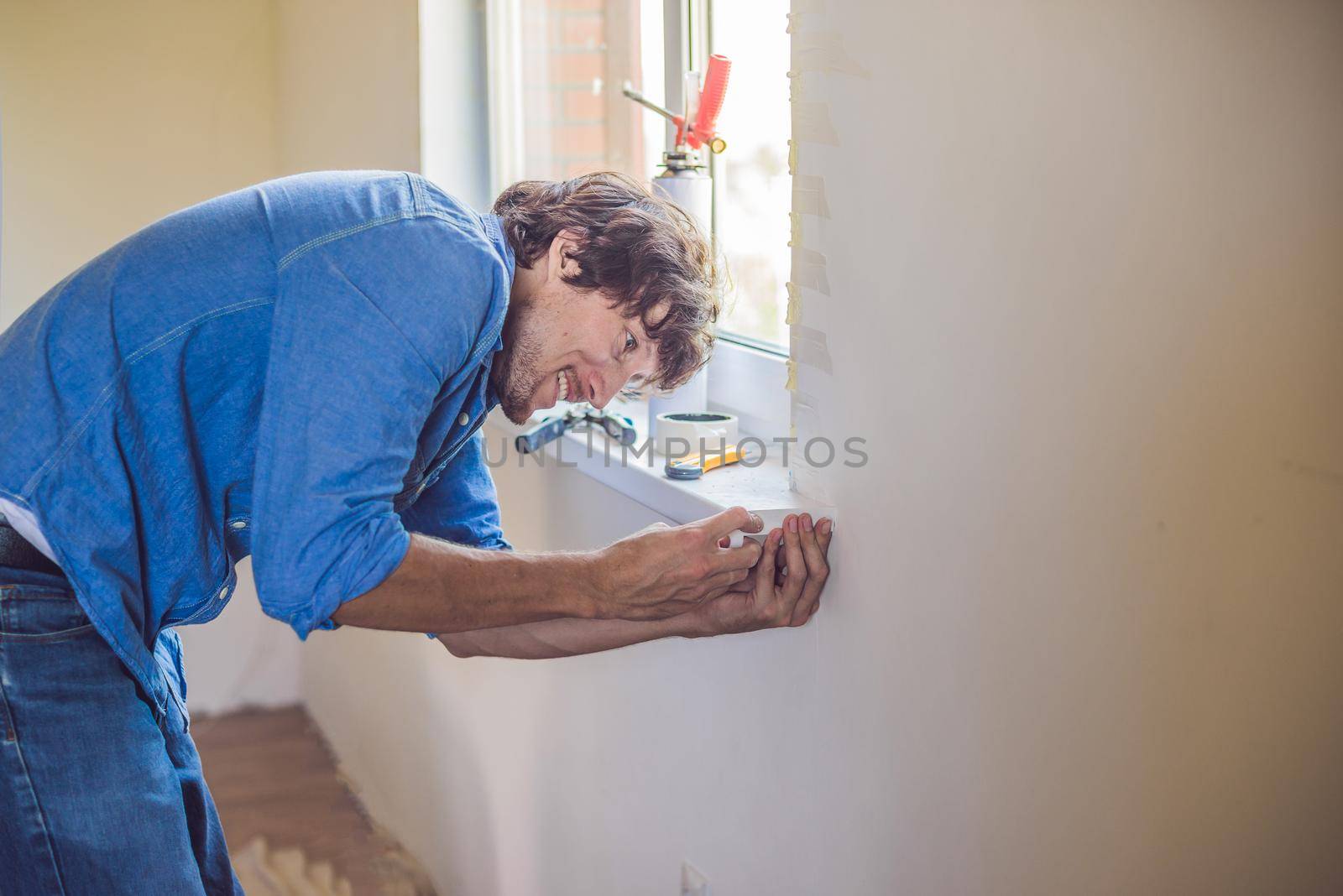 Man in a blue shirt does window installation.