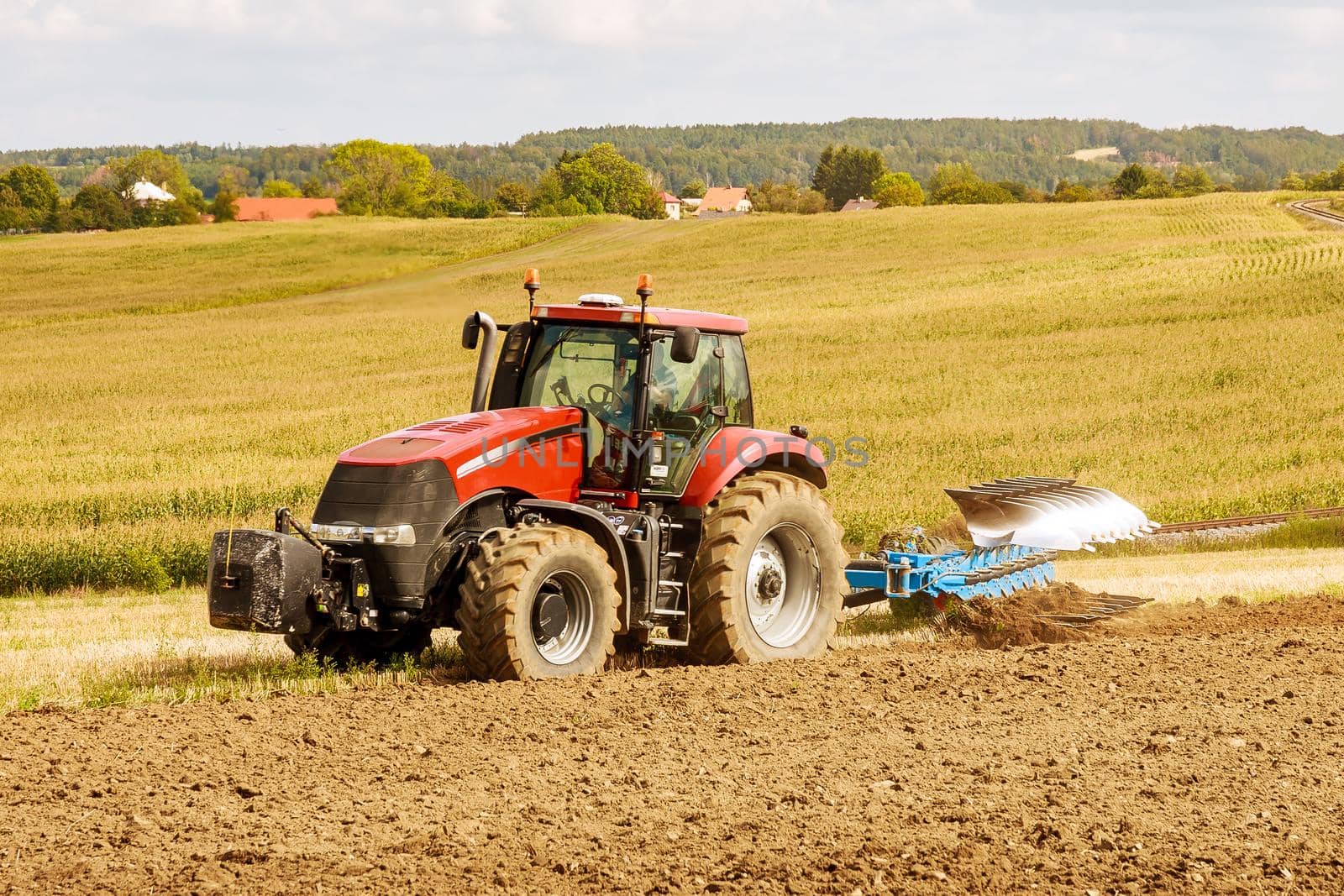 Farmer in red tractor preparing land for sowing