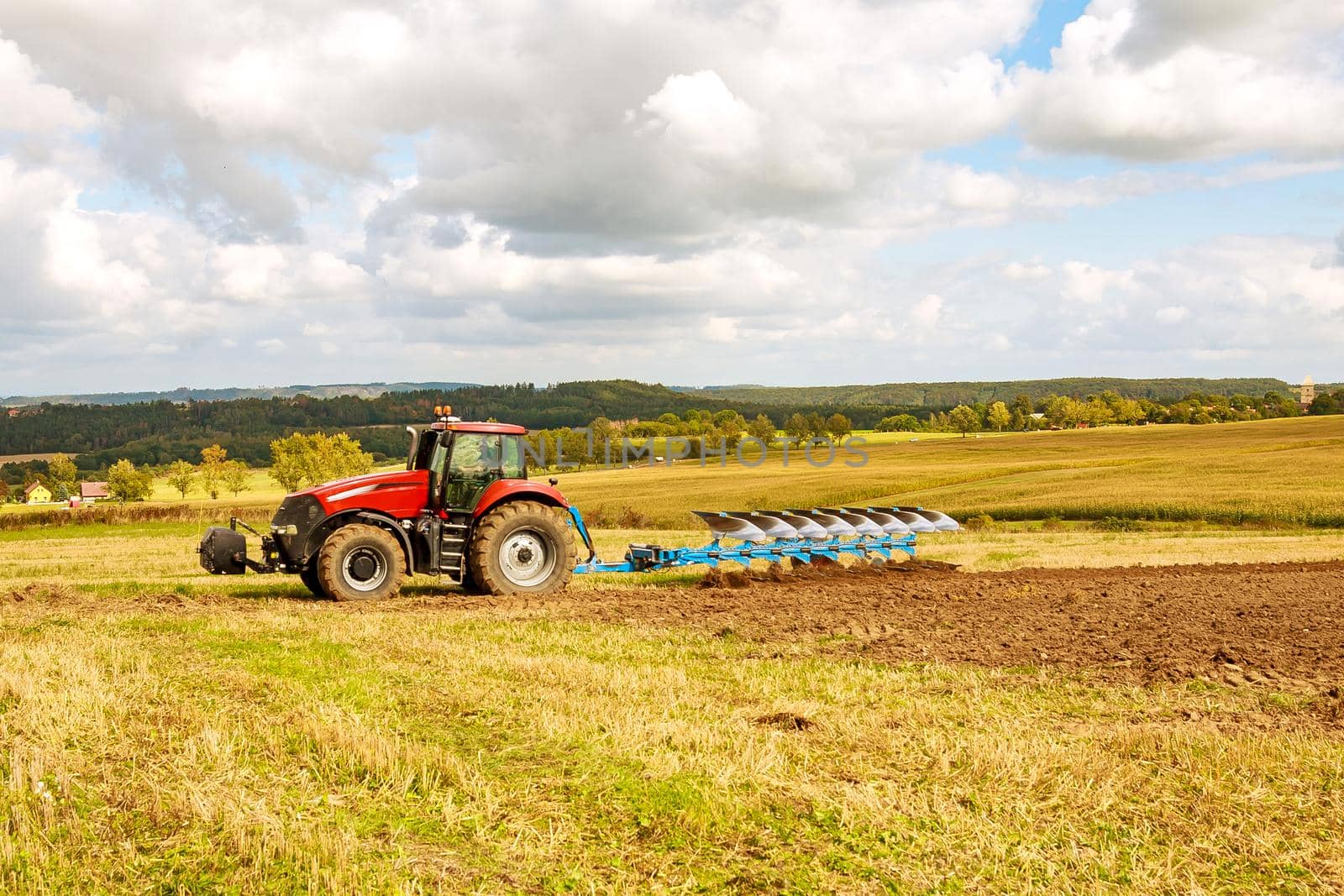 Farmer in red tractor preparing land for sowing