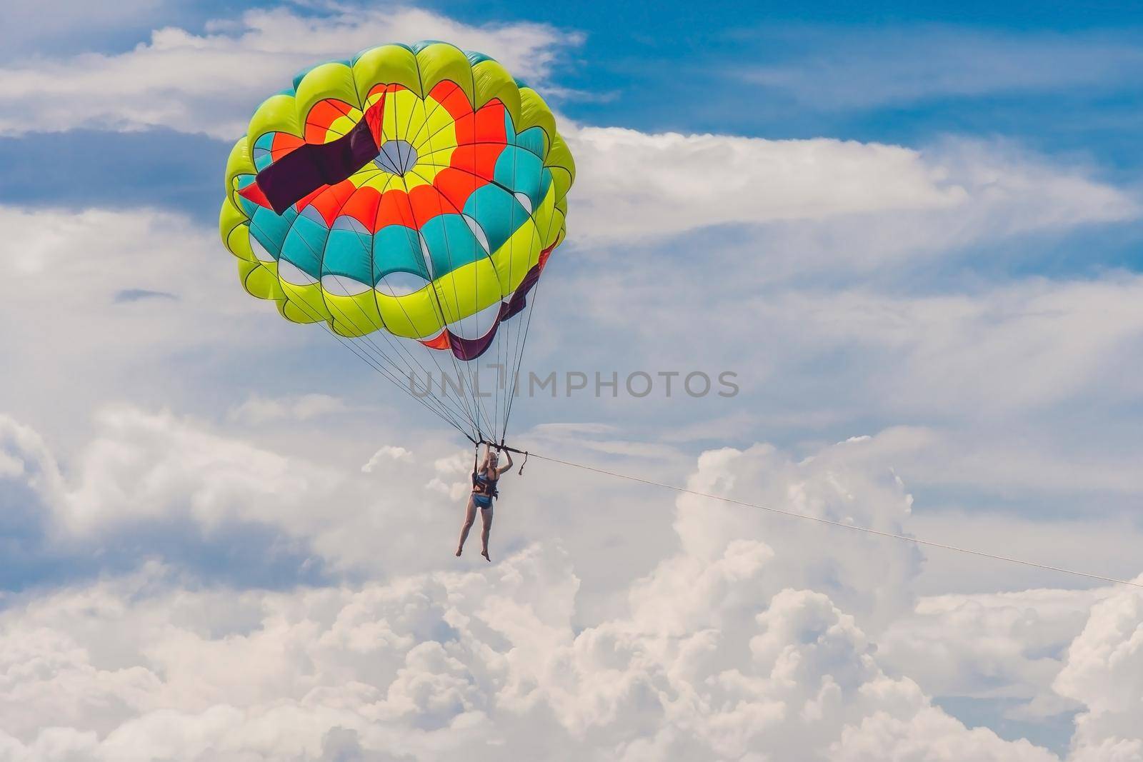 Young woman flies on a parachute among the clouds.
