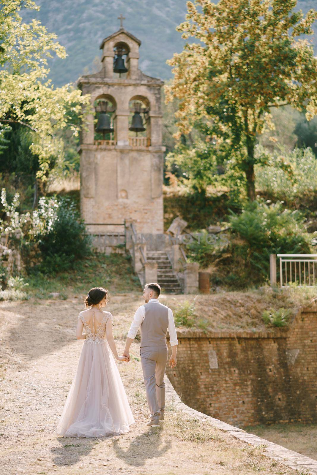 Groom and bride go to a small chapel in the garden of an old villa by Nadtochiy