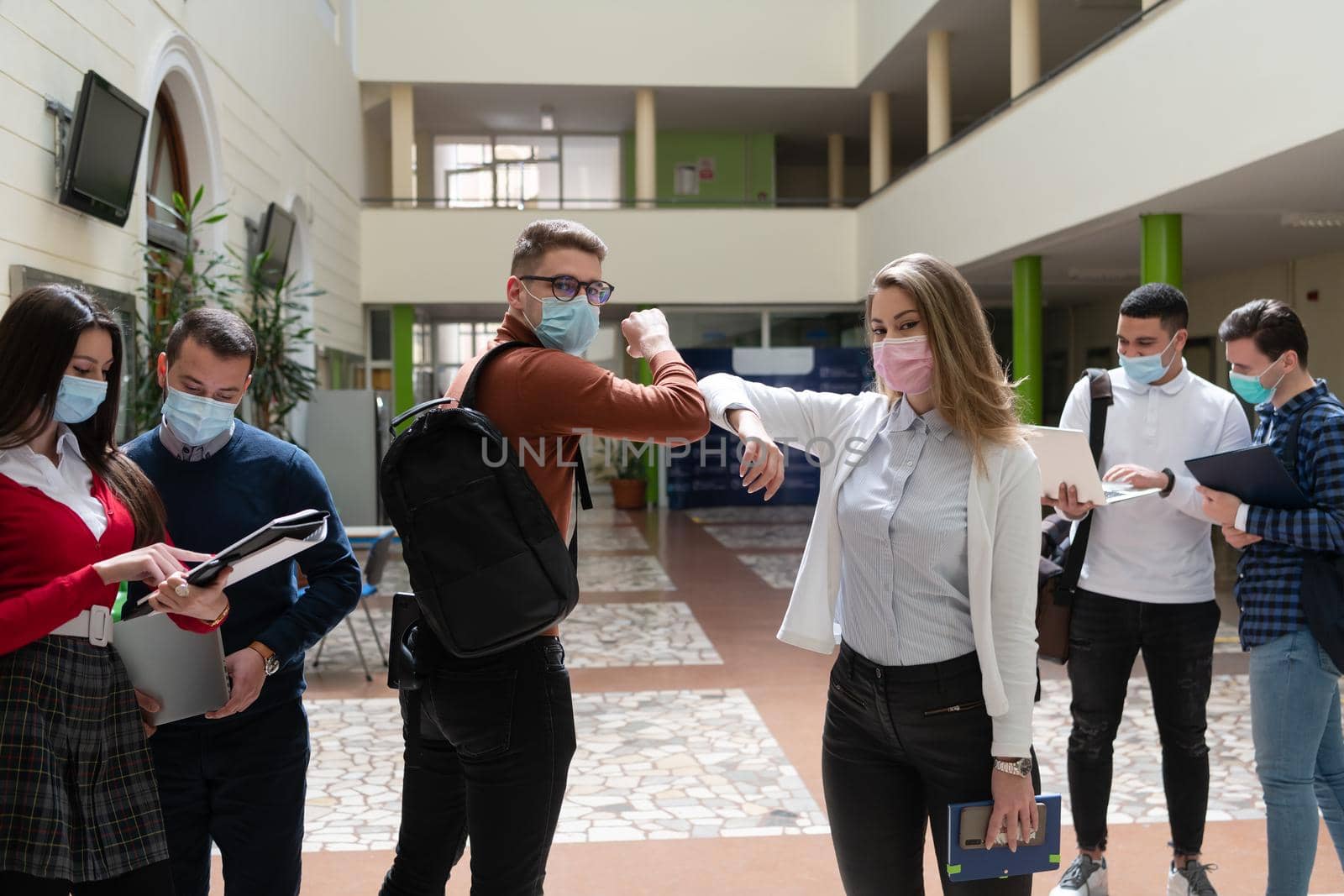 University students group greeting new normal coronavirus education lifestyle handshake and elbow bumping while wearing protective face masks