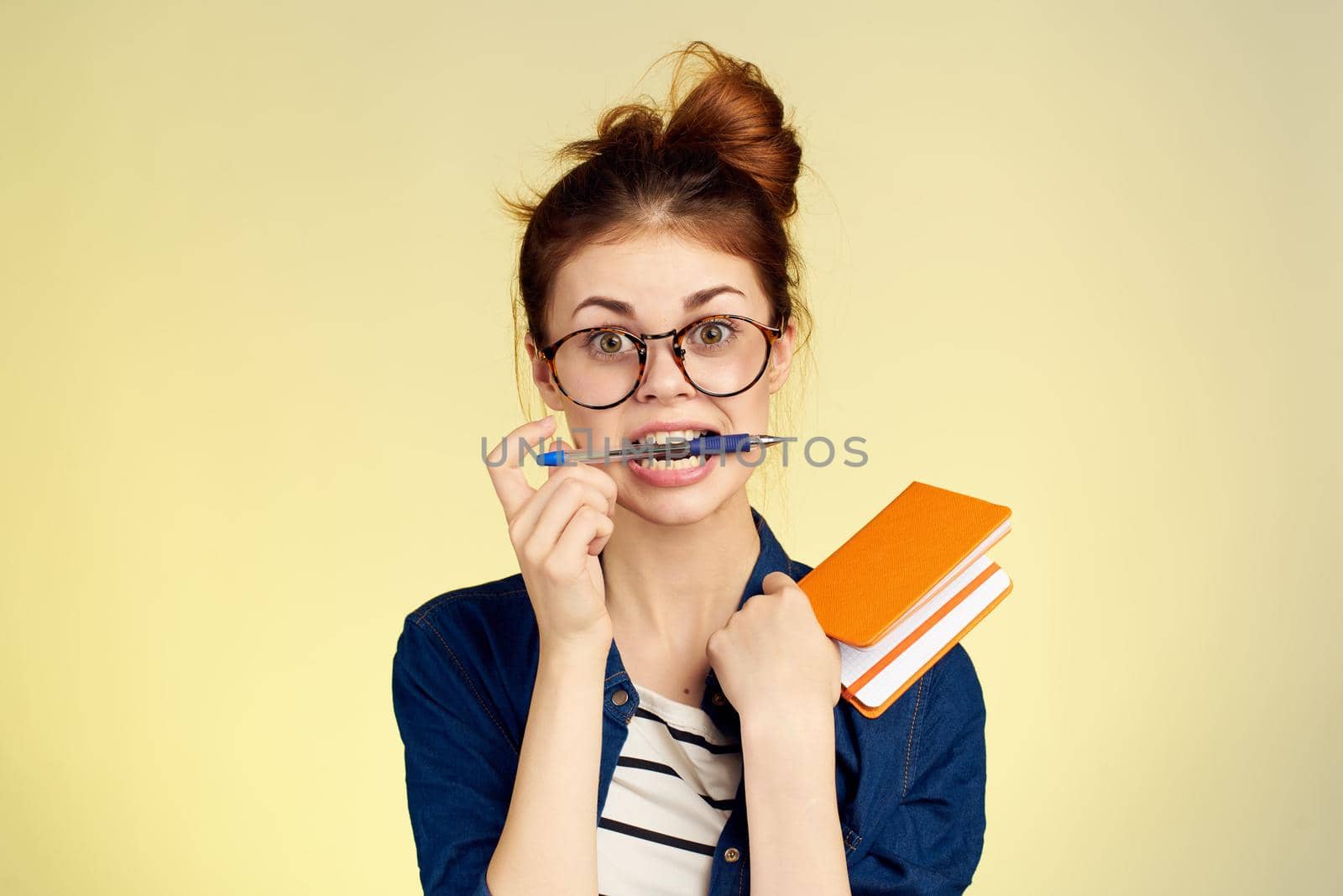 woman student with glasses notepad with pen yellow background. High quality photo