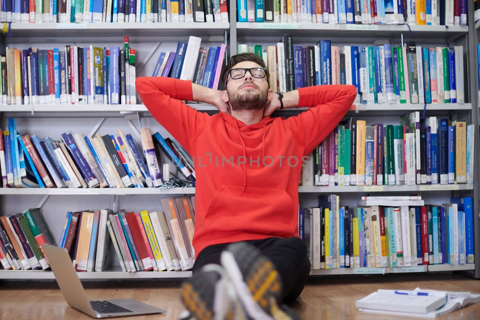 a young student with glasses sits in the libraryand making break of teaching
