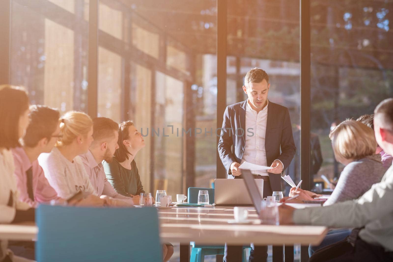 Group of a young business people brainstorming and discussing business plan on meeting at sunny bright office interior