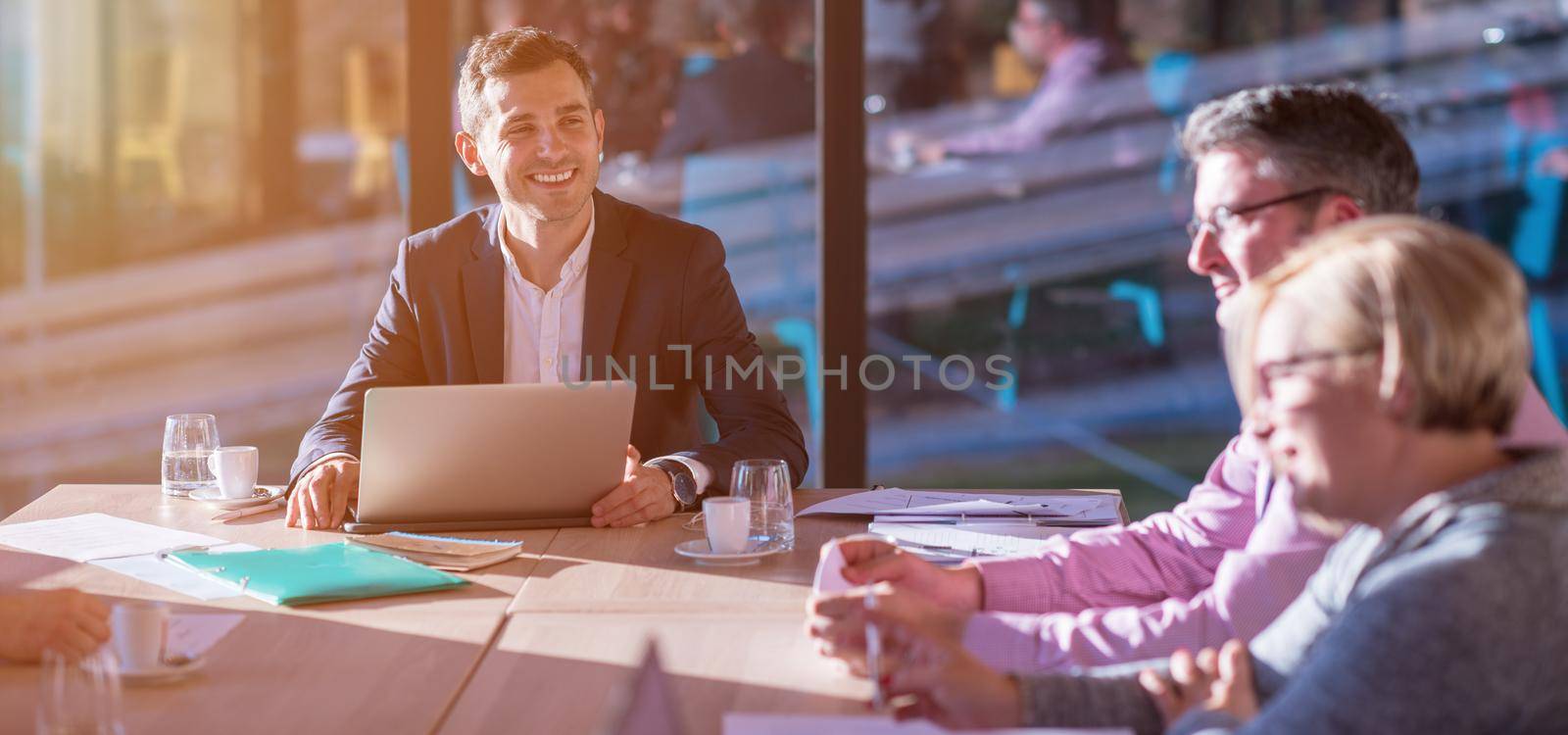 Group of a young business people brainstorming and discussing business plan on meeting at sunny bright office interior