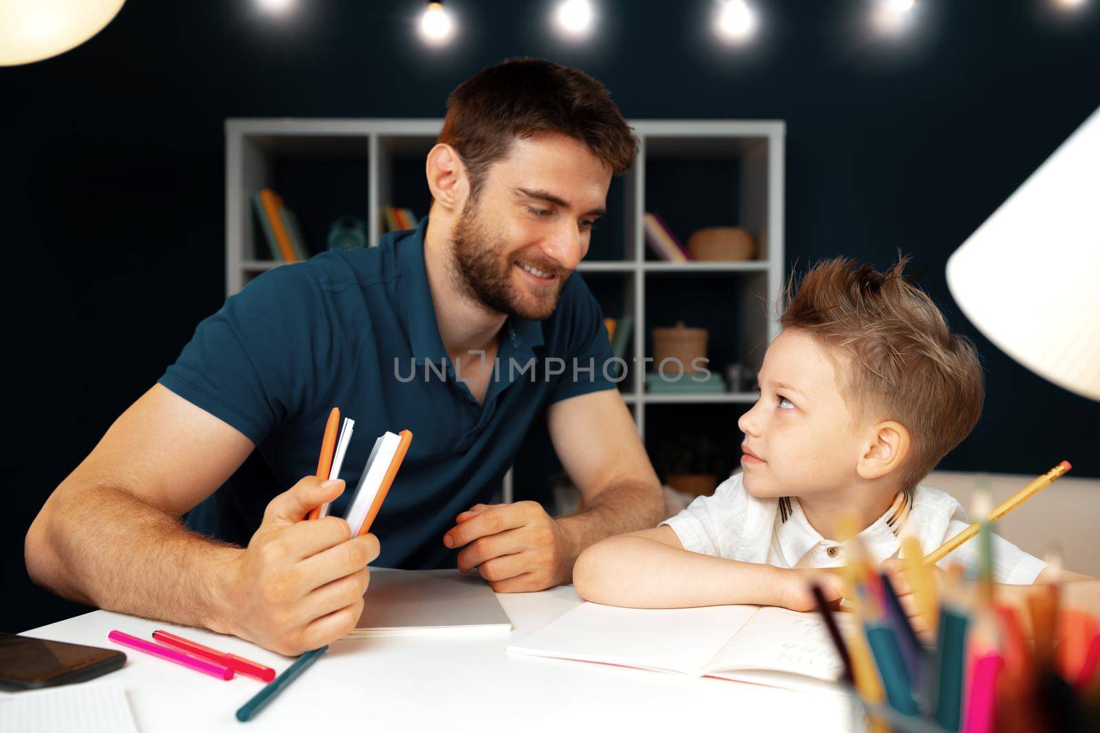Father helping his little son with school homework close up