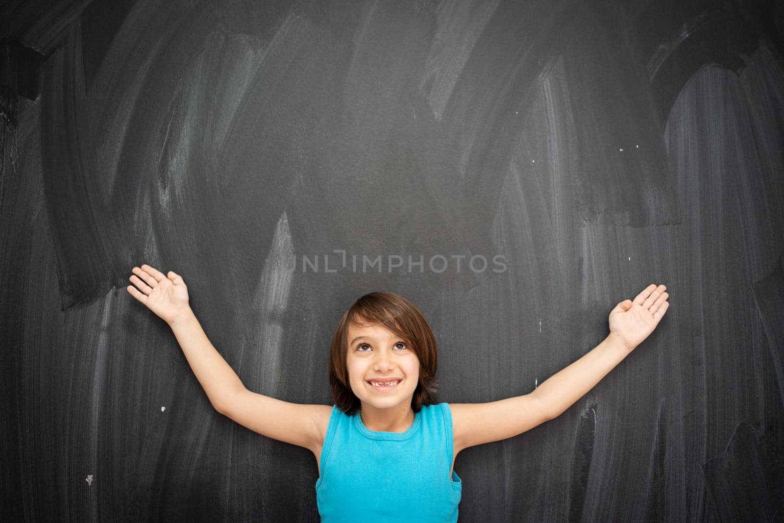 Little cute boy in front of classroom chalkboard