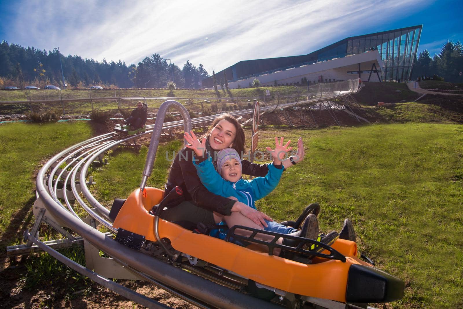 young mother and son driving alpine coaster by dotshock
