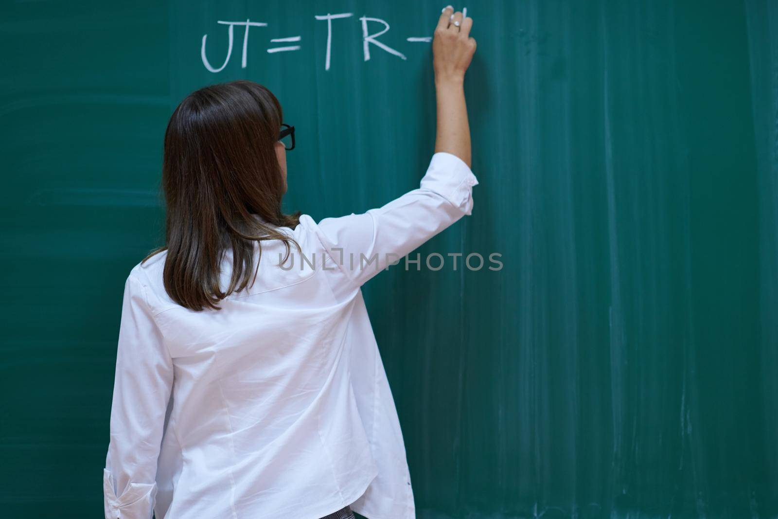 an attractive teacher with glasses explains to the students how to do the task on the board