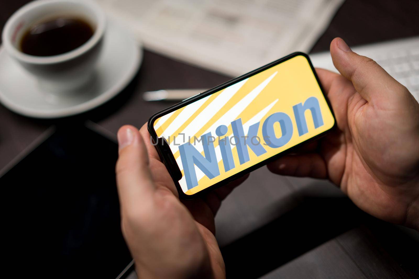 New York, New York / USA - 11 11 2019: Logo of Nikon on the iPhone X in hands in office