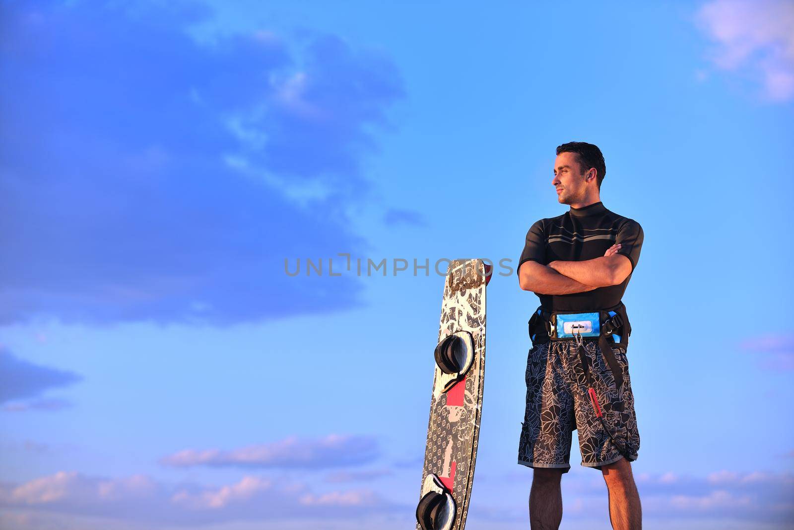 Portrait of a strong young  surf  man at beach on sunset in a contemplative mood with a surfboard