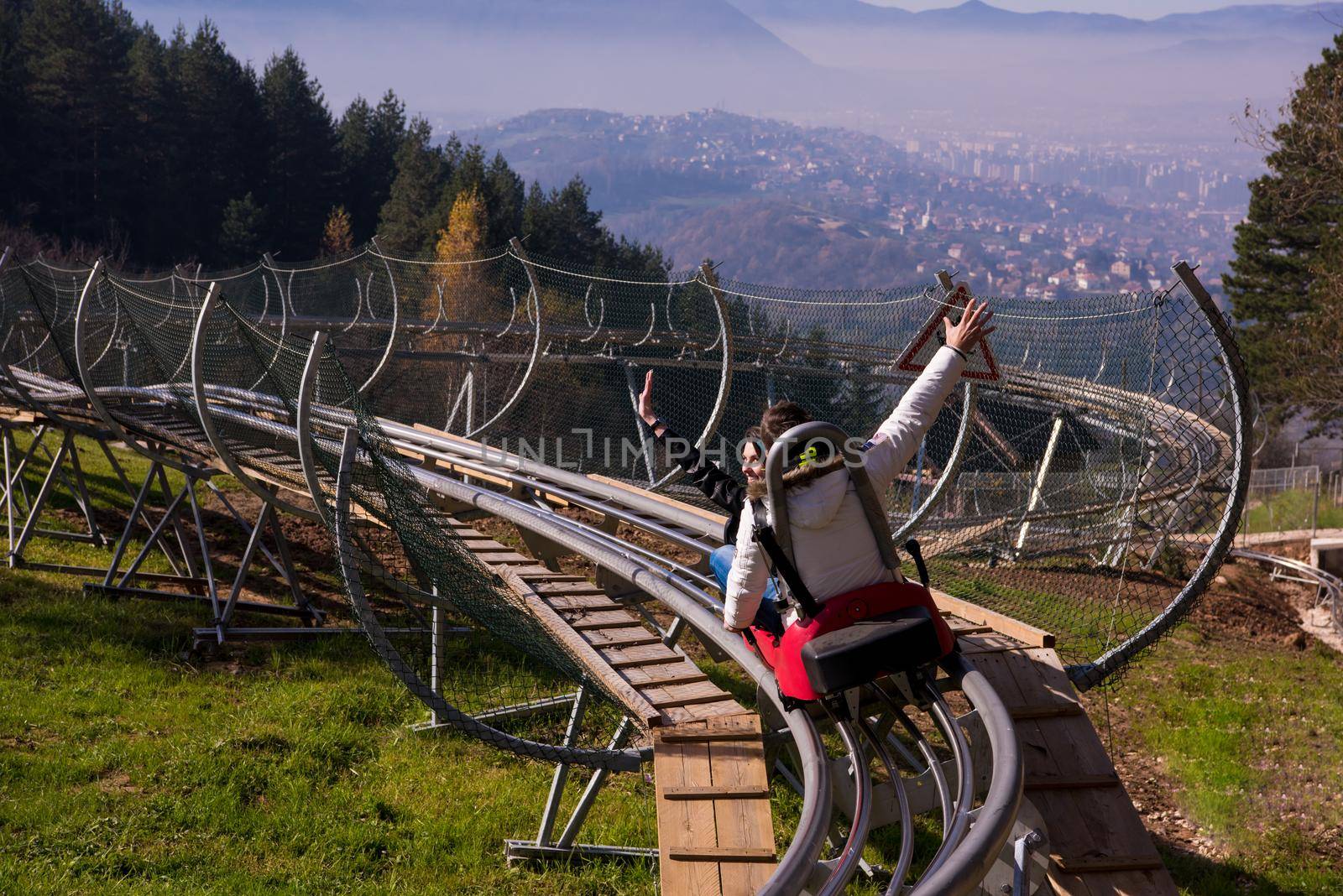 Excited young couple driving alpine coaster while enjoying beautiful sunny day in the nature