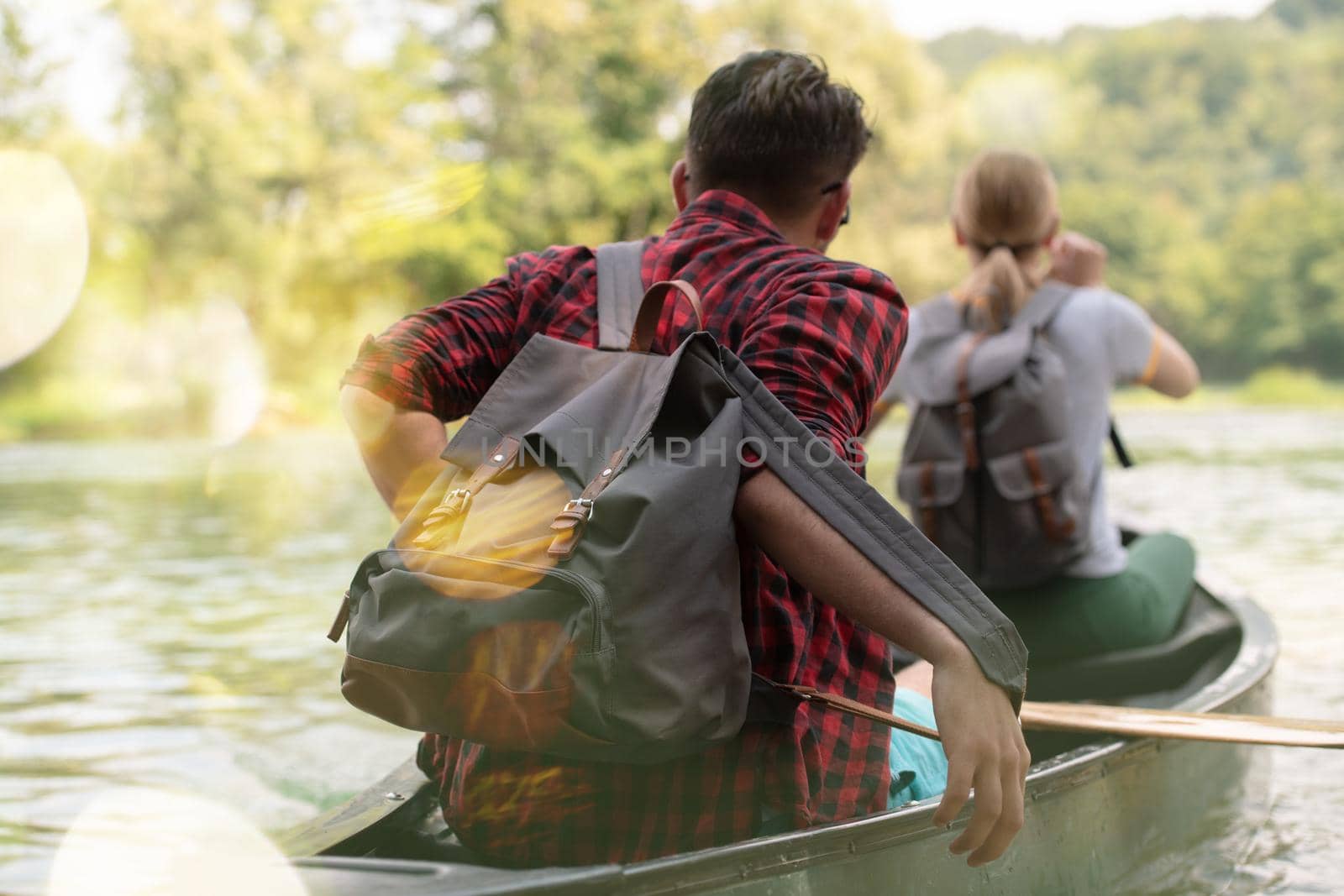 Couple adventurous explorer friends are canoeing in a wild river surrounded by the  beautiful nature