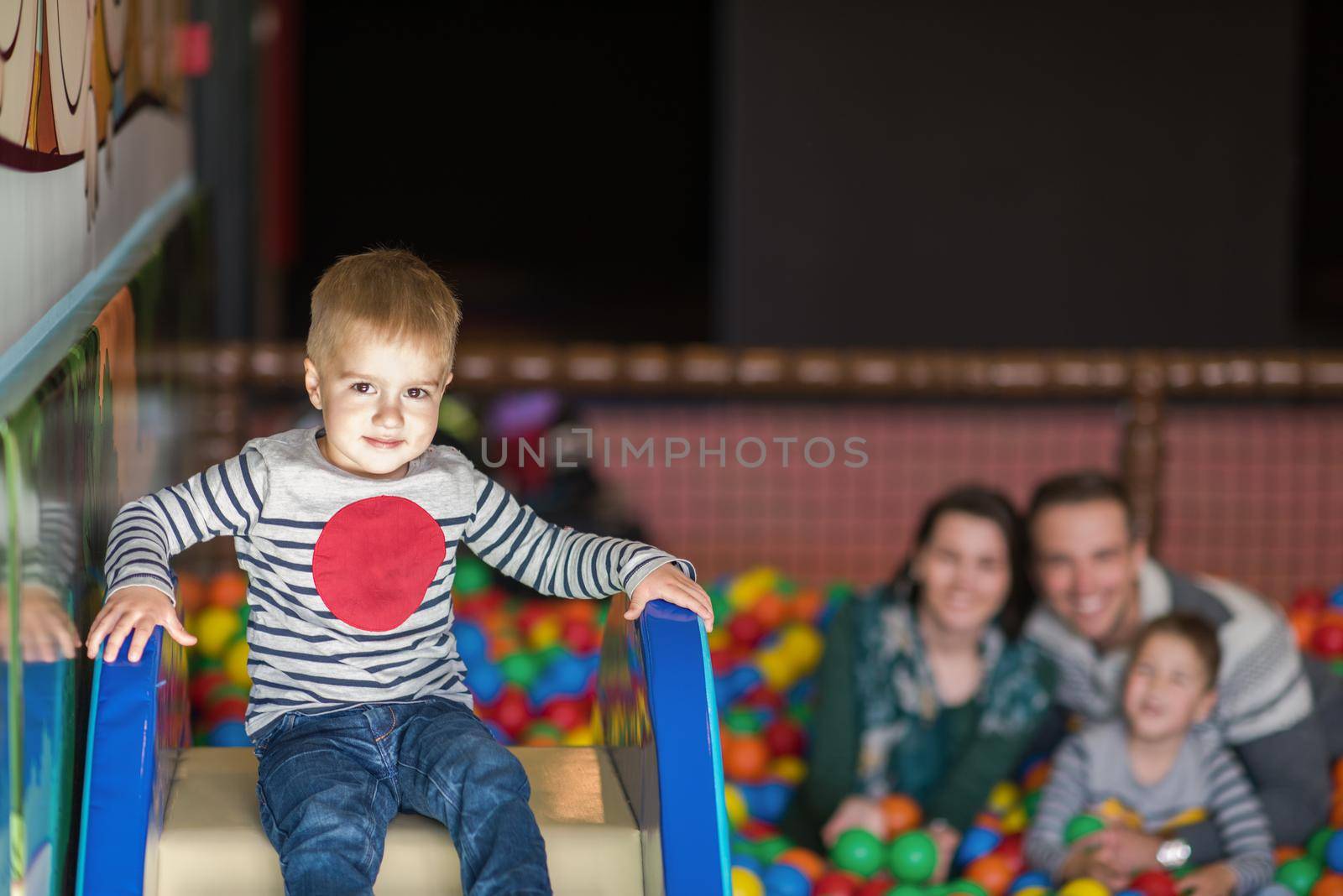 happy family enjoying free time young parents and kids playing in the pool with colorful balls at childrens playroom