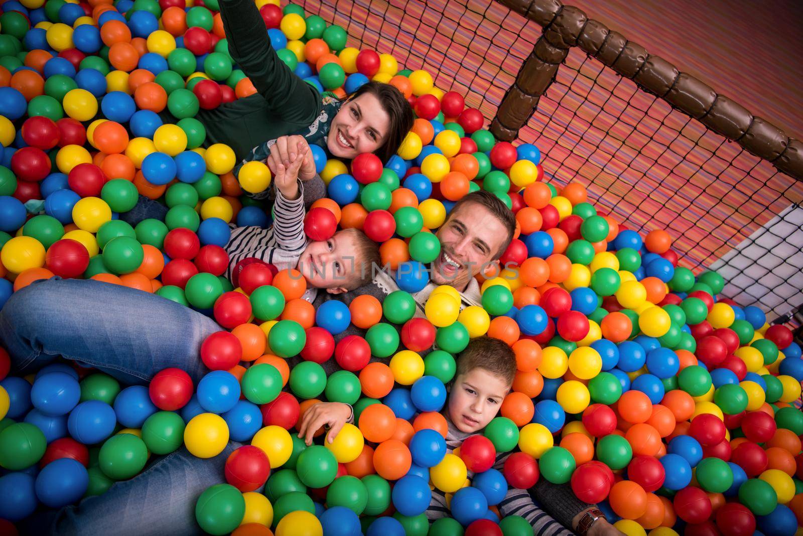 happy family enjoying free time young parents and kids playing in the pool with colorful balls at childrens playroom