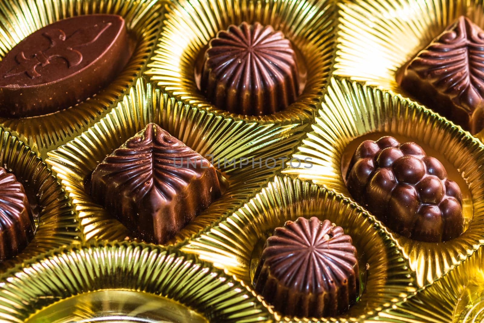 Variety of delicious chocolate pralines in a golden box. Close up of bonbons, selective focus.