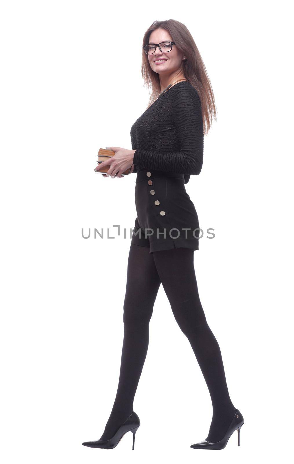 in full growth. a smiling young woman with a stack of books striding forward . isolated on a white background.