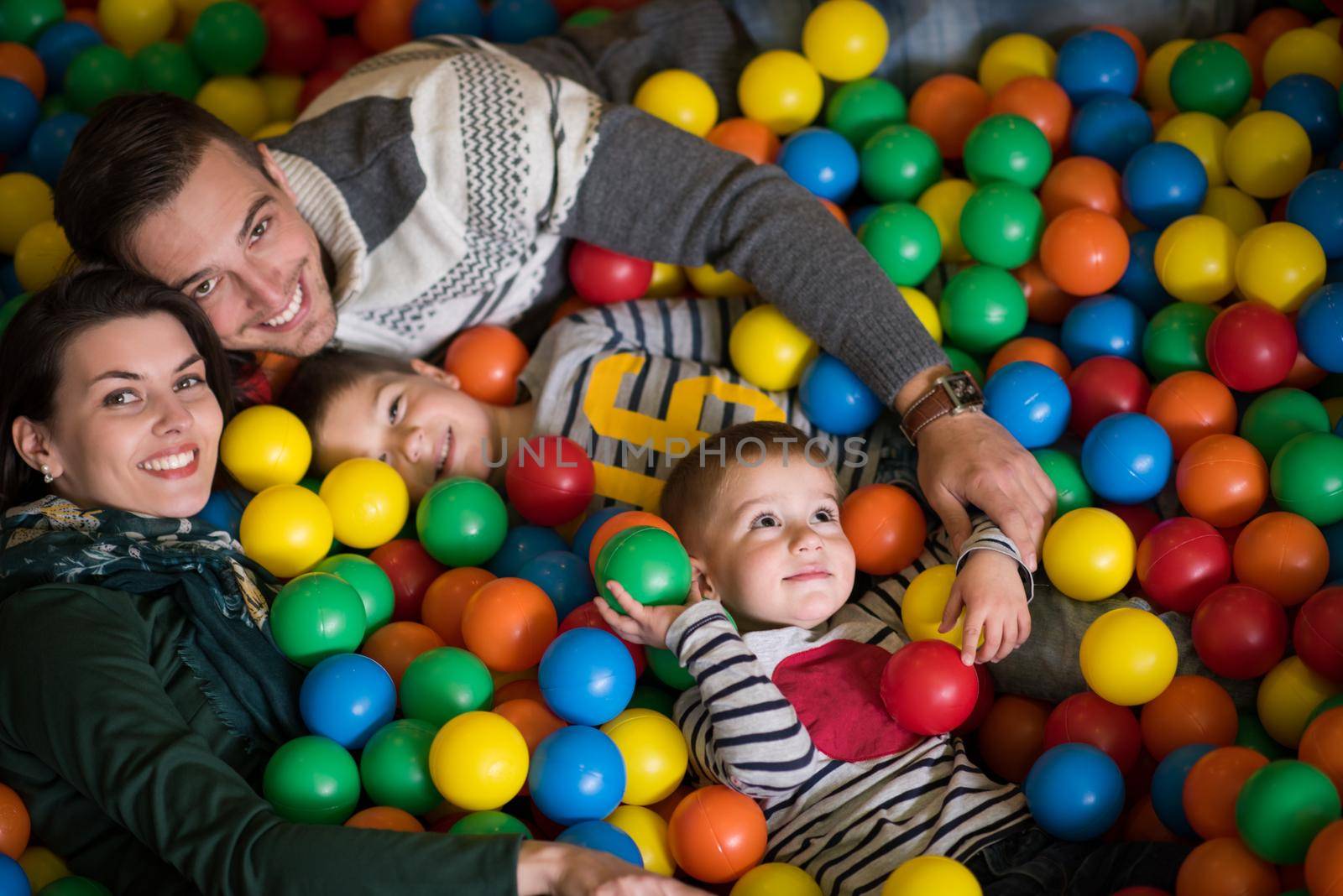 young parents with kids in a children's playroom by dotshock