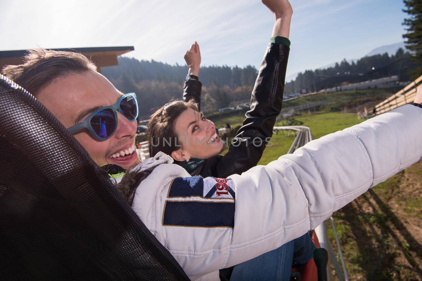 Excited young couple enjoys driving on alpine coaster