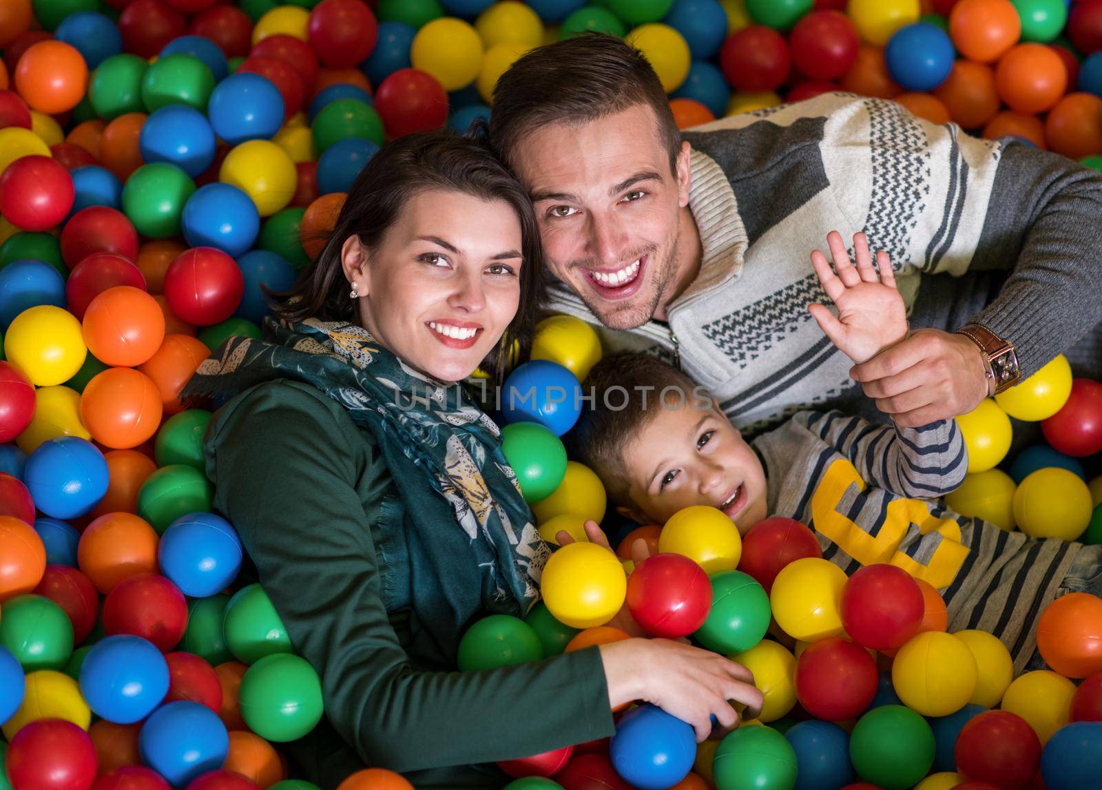 happy family enjoying free time young parents and kids playing in the pool with colorful balls at childrens playroom