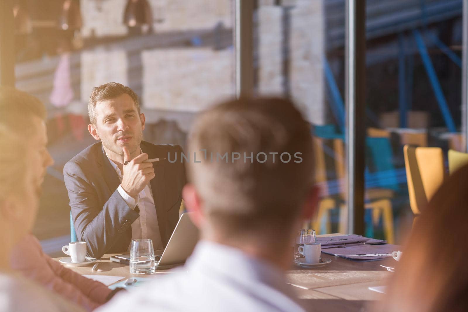 Group of a young business people brainstorming and discussing business plan on meeting at sunny bright office interior