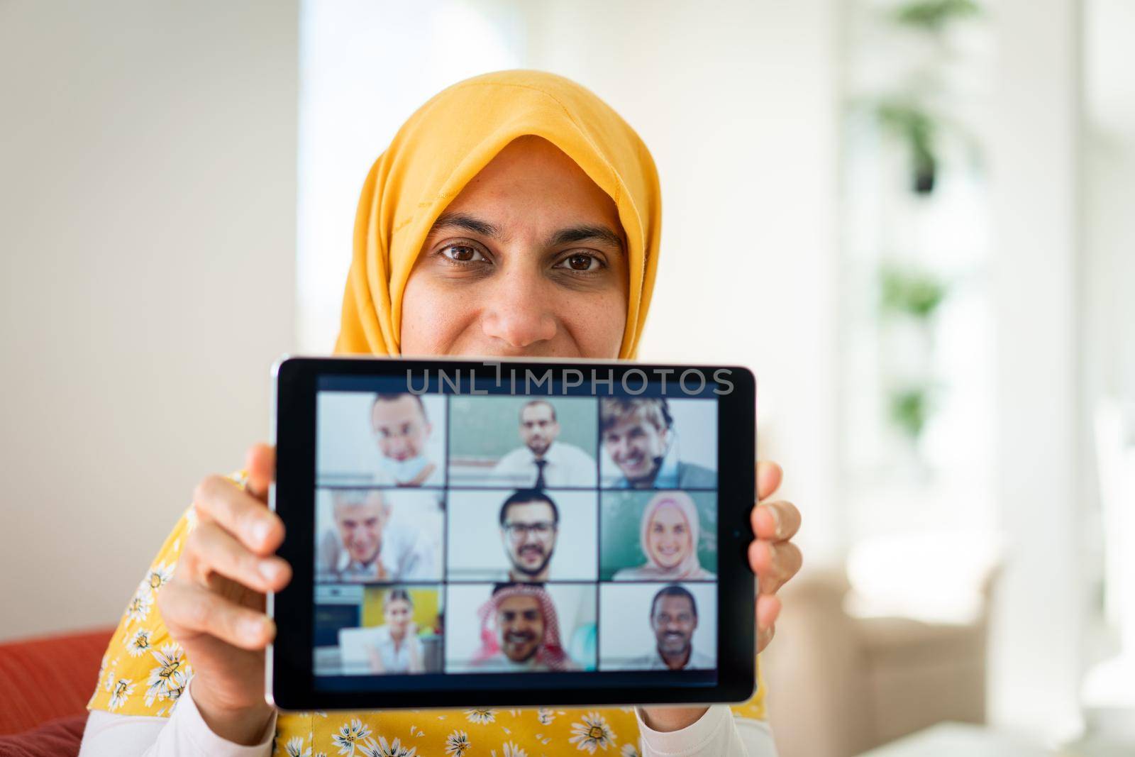 Muslim womah holding tablet with zoom conference screen