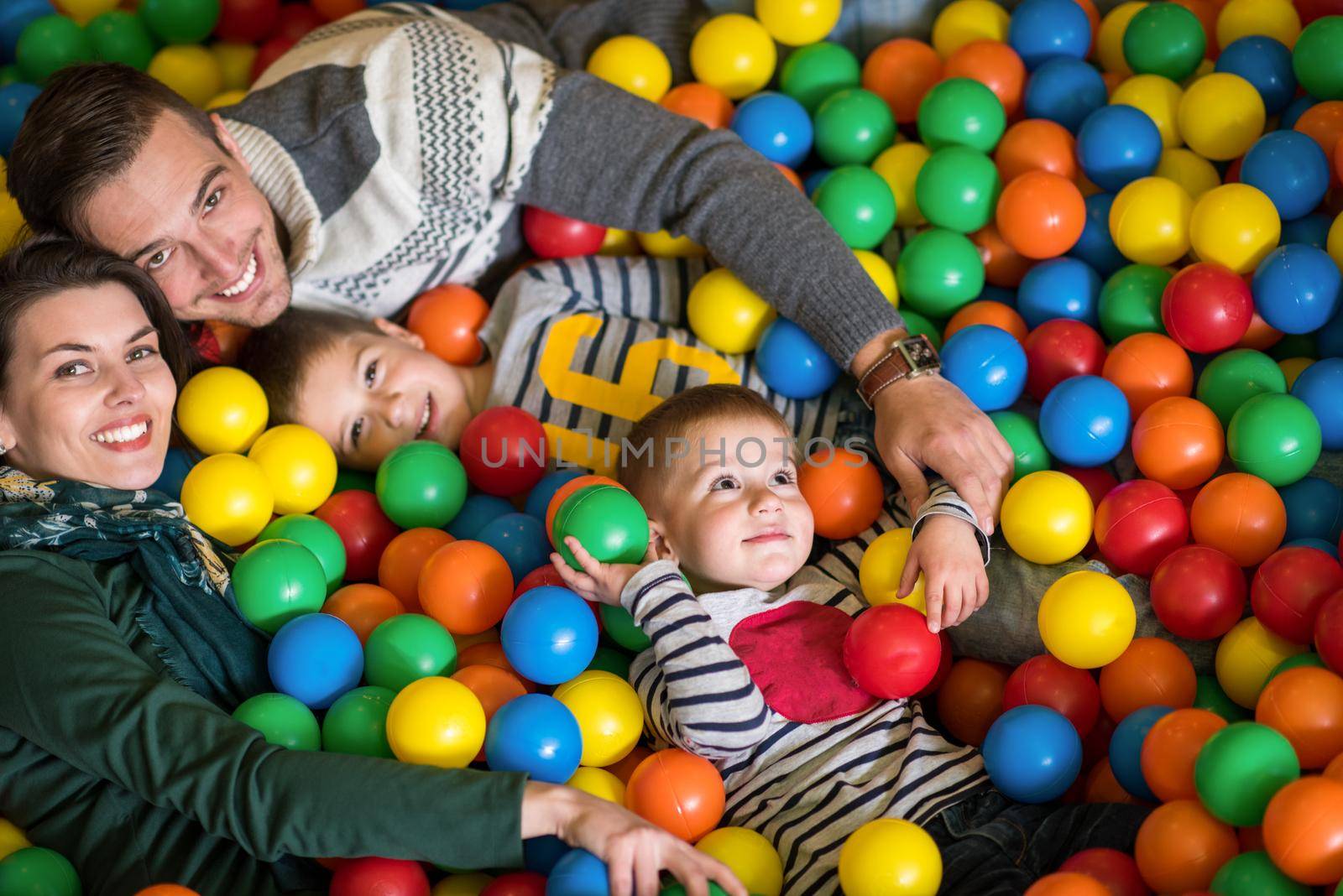 happy family enjoying free time young parents and kids playing in the pool with colorful balls at childrens playroom