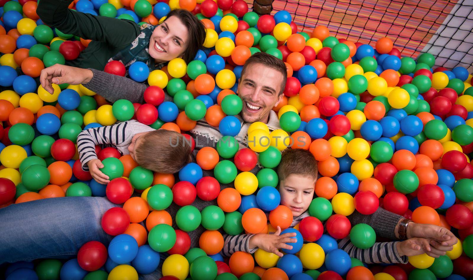 parents and kids playing in the pool with colorful balls by dotshock