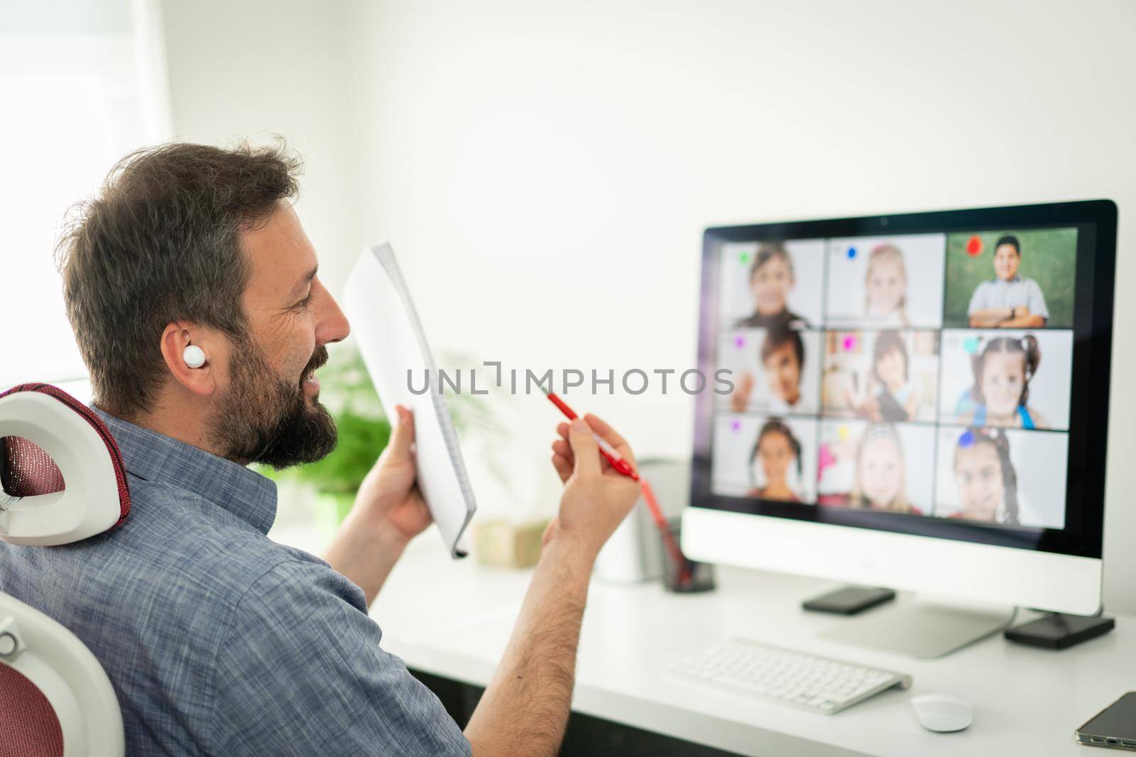 Male teacher having online conference with school children working at home