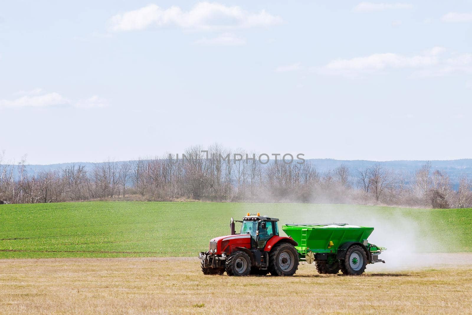 Agricultural work. Tractor spreading fertilizer on grass field.