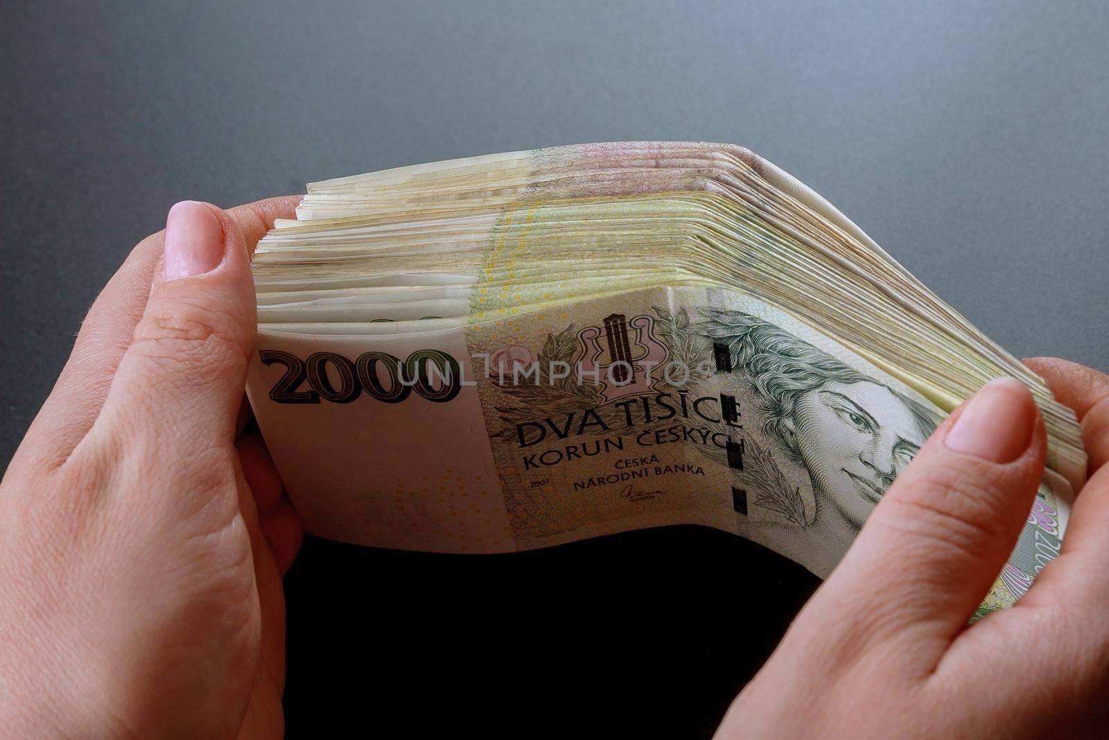 Bundle of Czech money in the hands of a woman on a black background. Banknotes of 2000.