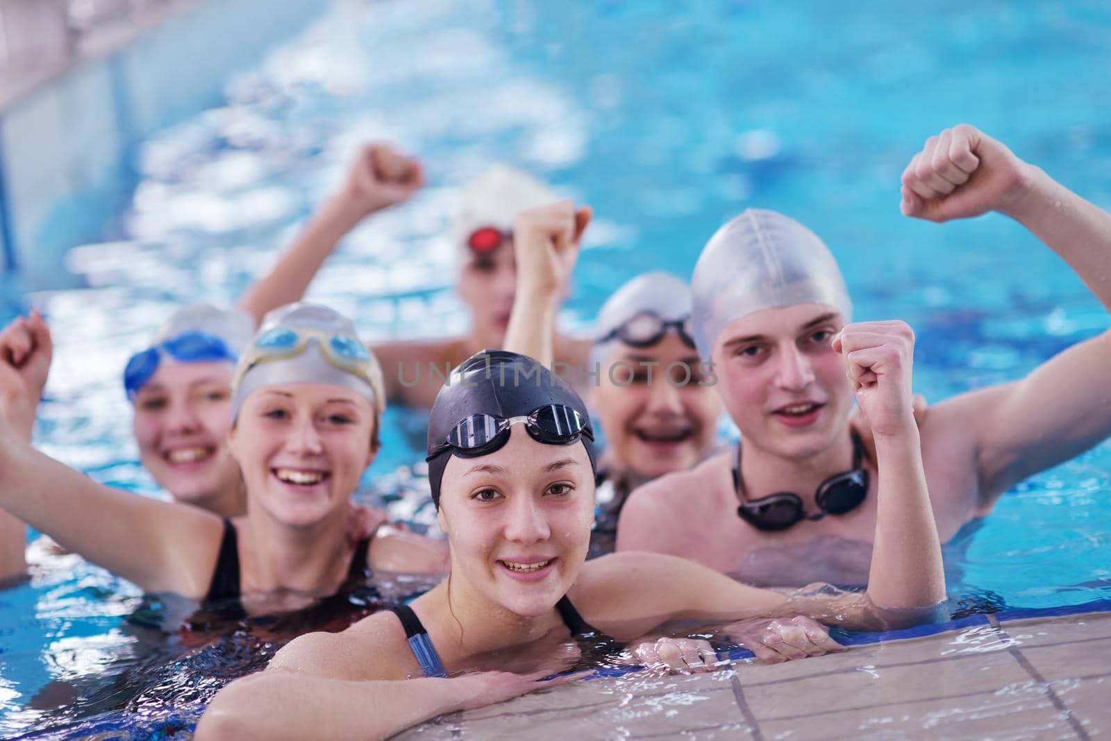 happy teen  group  at swimming pool class  learning to swim and have fun