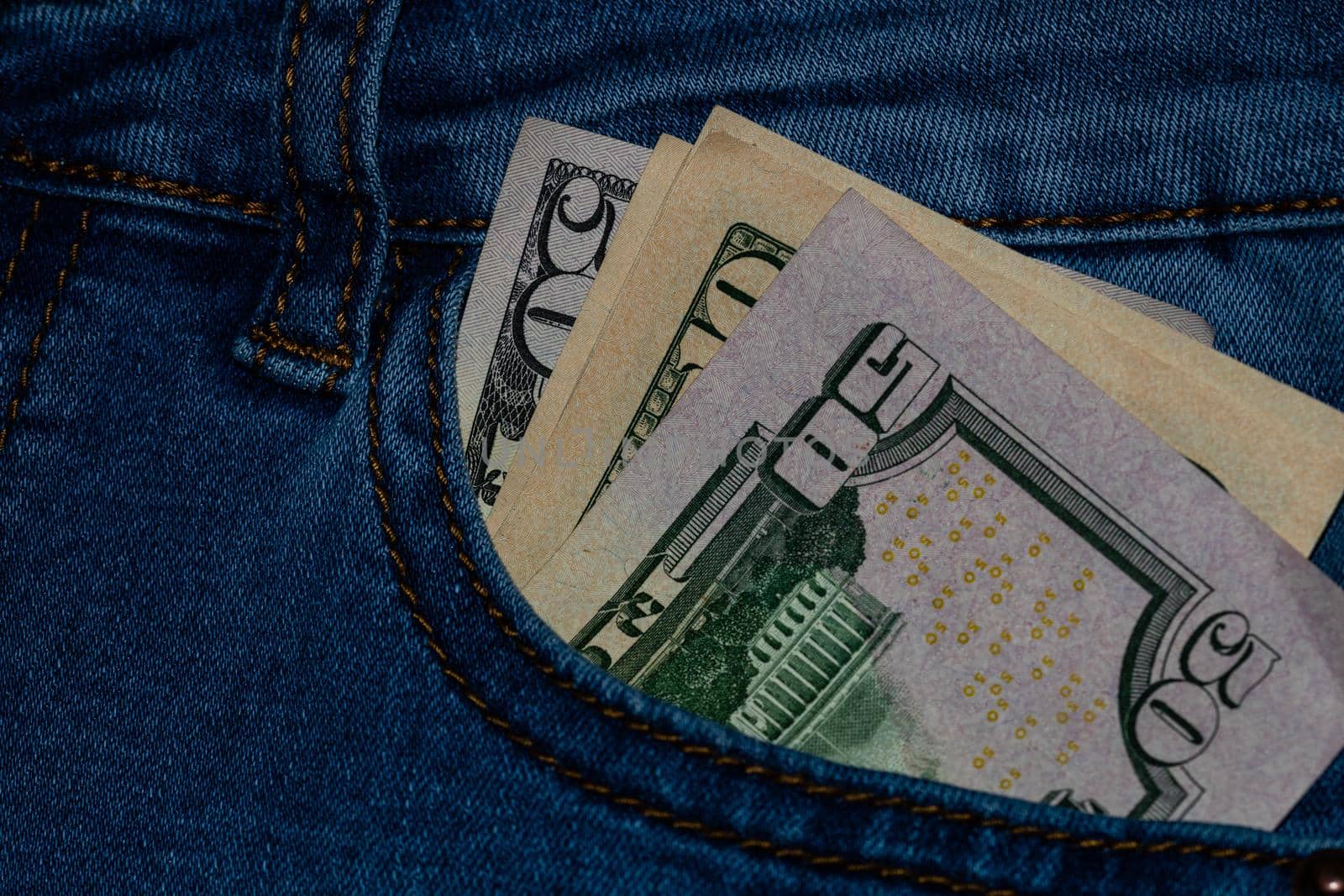 Banknotes, money in a jeans pocket, close up. Money stick out of the jeans pocket, finance and currency concept. Concept of rich people, saving or spending money.