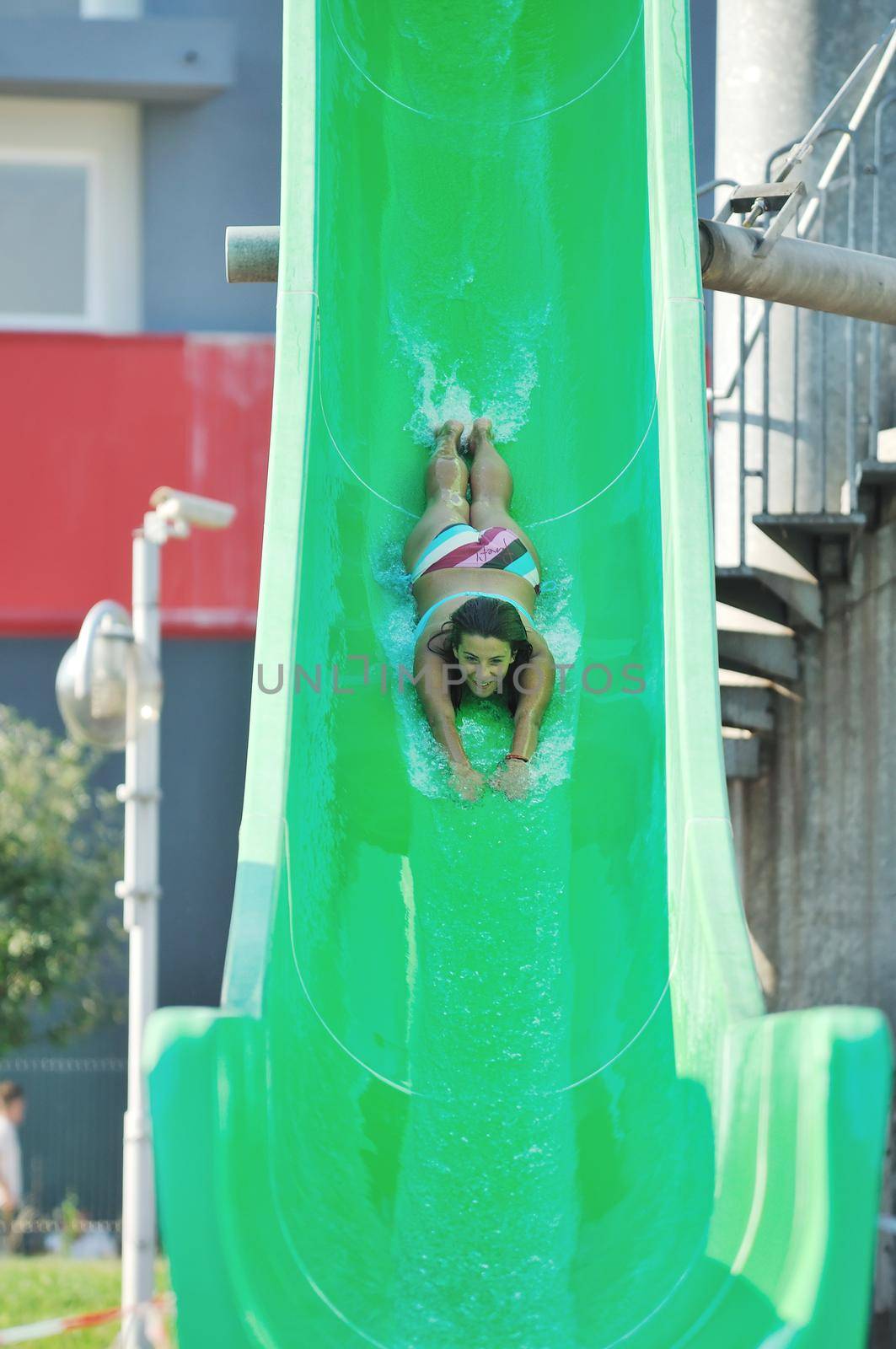 girl have fun  on water slide at outdoor swimming pool by dotshock