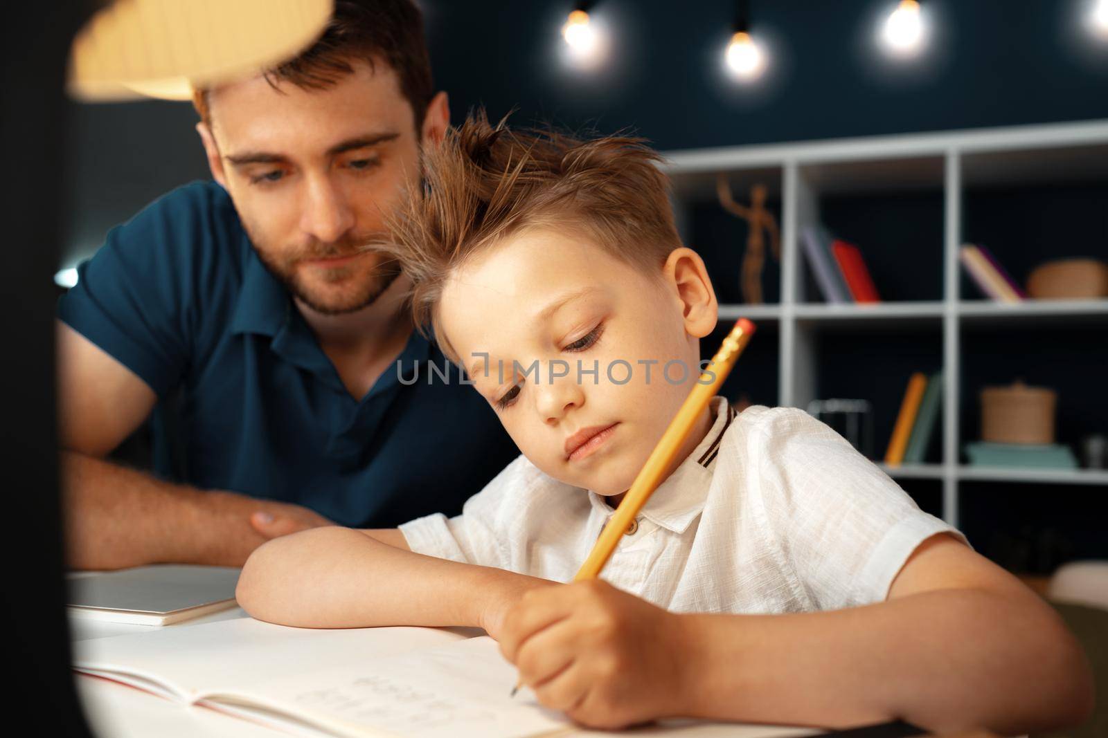 Dad and son doing school homework together sitting at the table