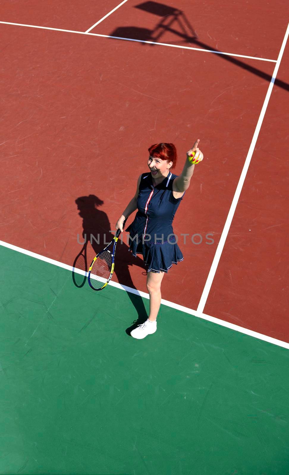 young fit woman play tennis outdoor on orange tennis field at early morning