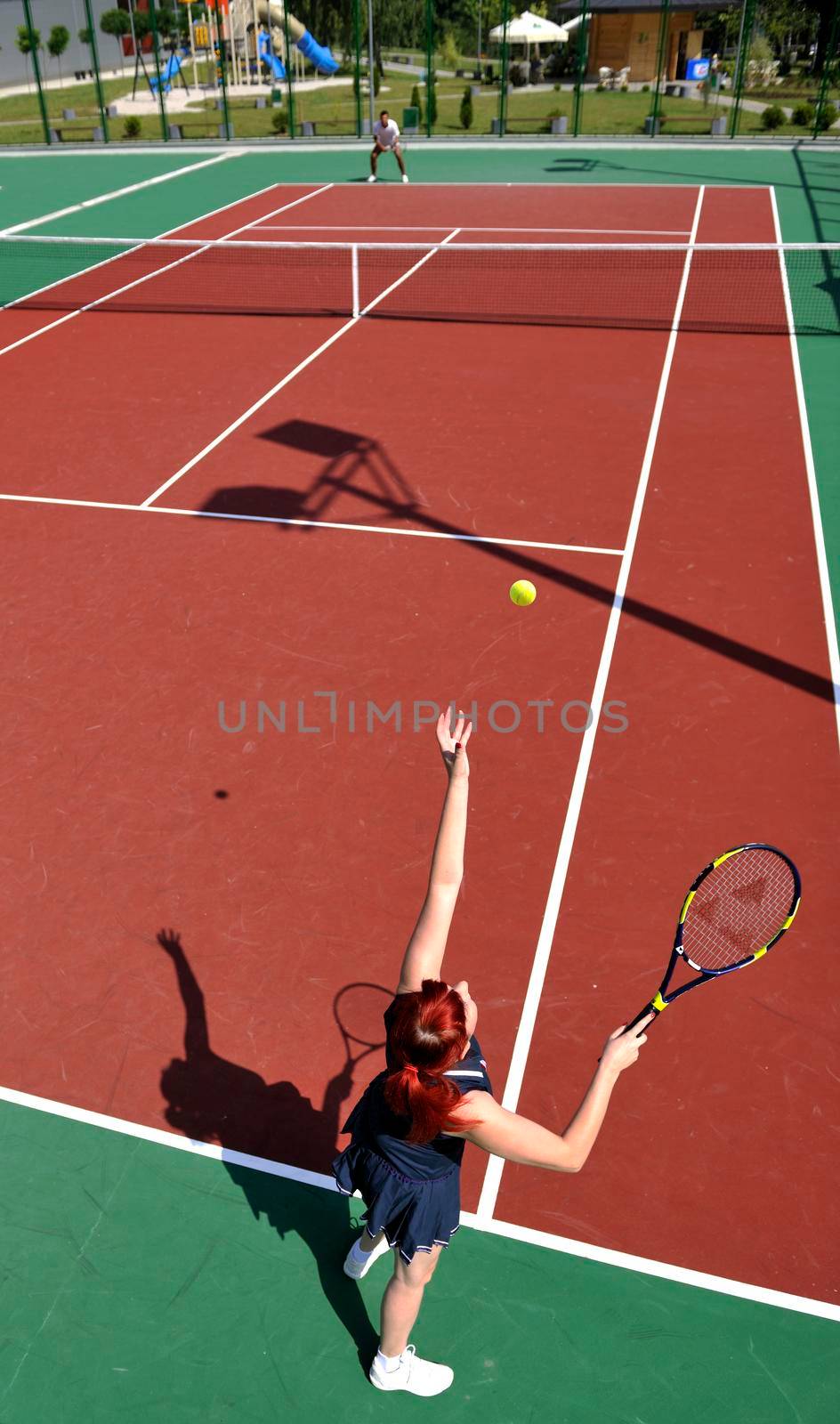 young fit woman play tennis outdoor on orange tennis field at early morning