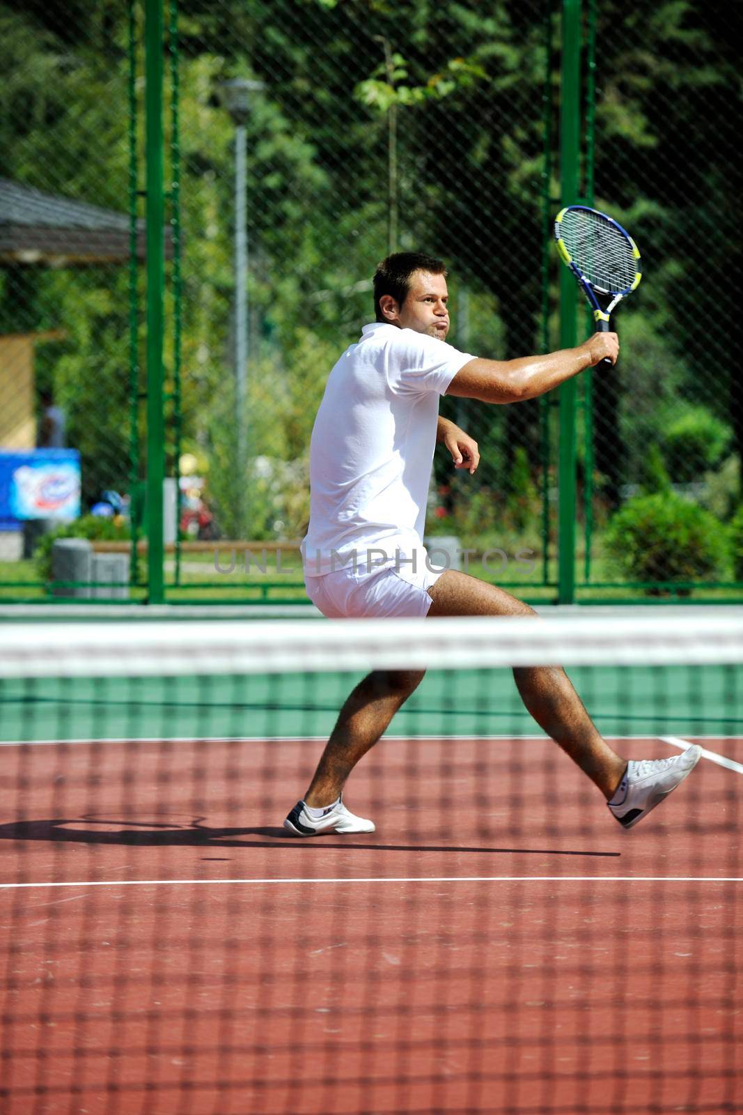 young man play tennis outdoor by dotshock