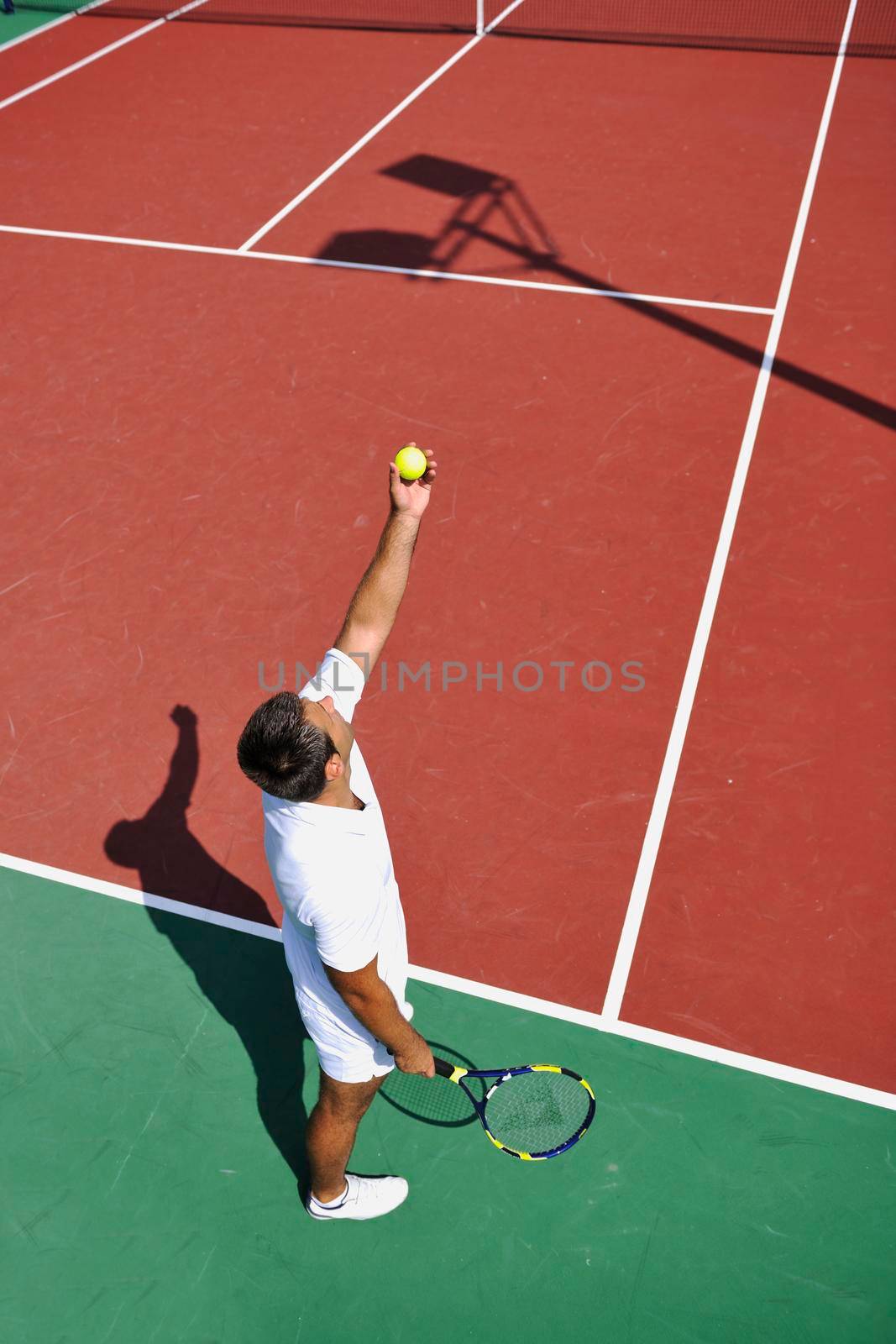 young man play tennis outdoor on orange tennis court at early morning