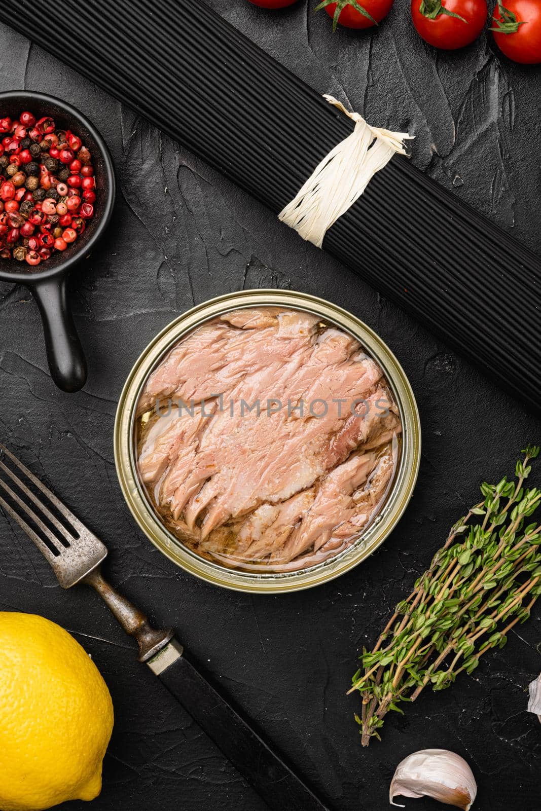 Open tuna tin set, on black dark stone table background, top view flat lay