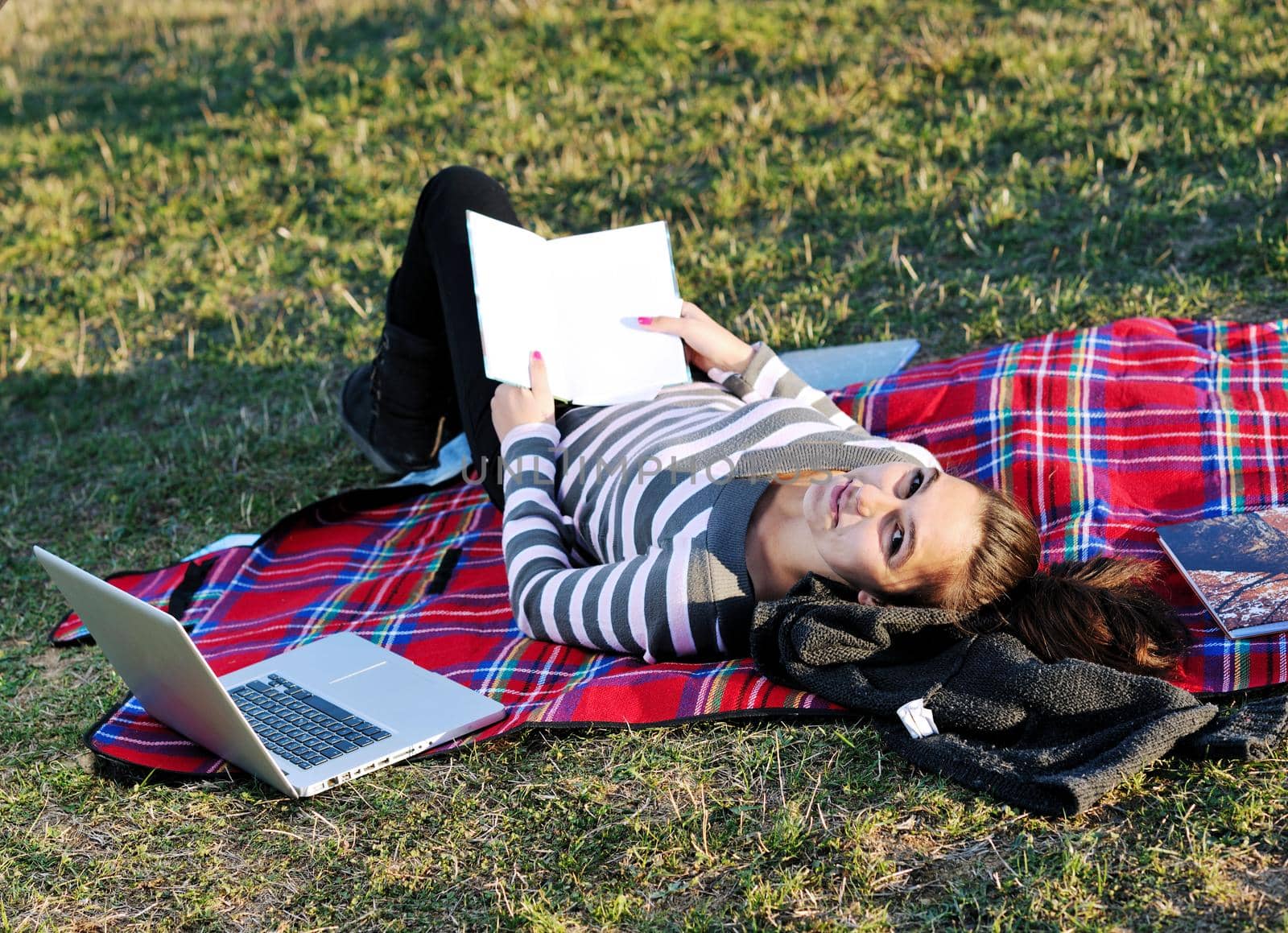 young teen girl read book and study homework outdoor in nature with blue sky in background