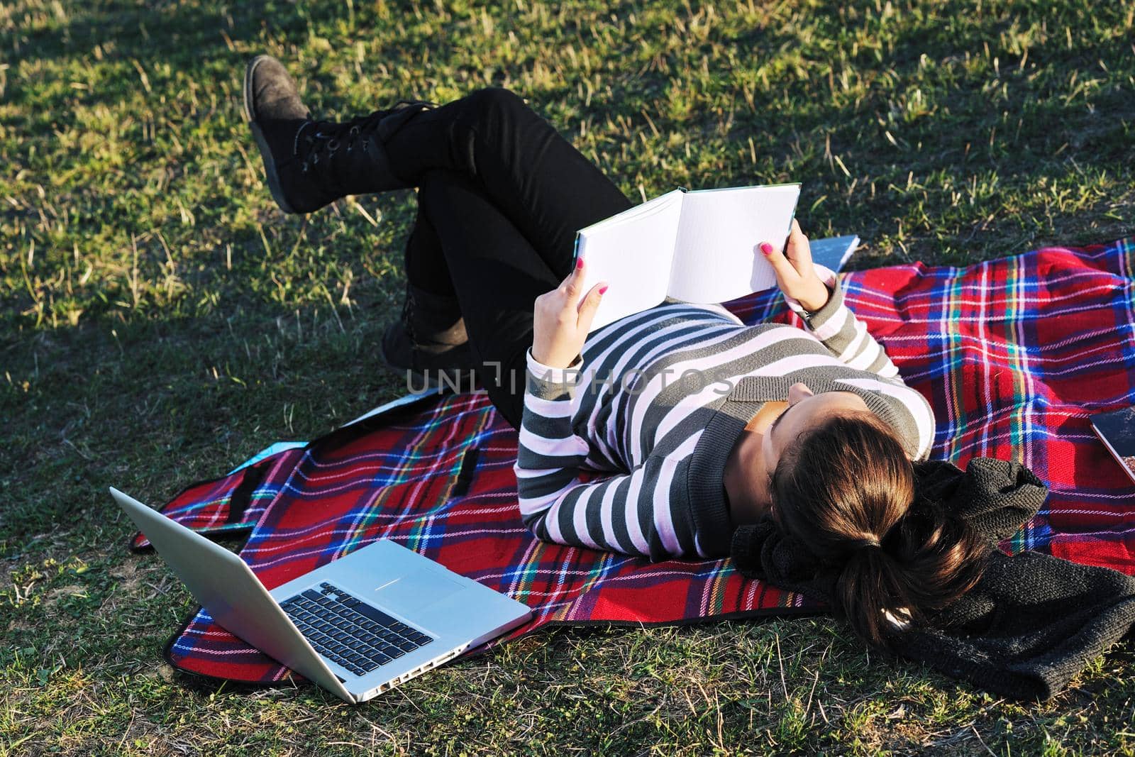 young teen girl read book and study homework outdoor in nature with blue sky in background