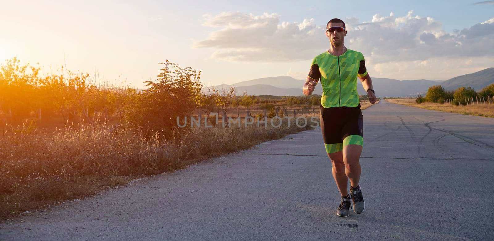 triathlon athlete running  on morning training sunrise in the background