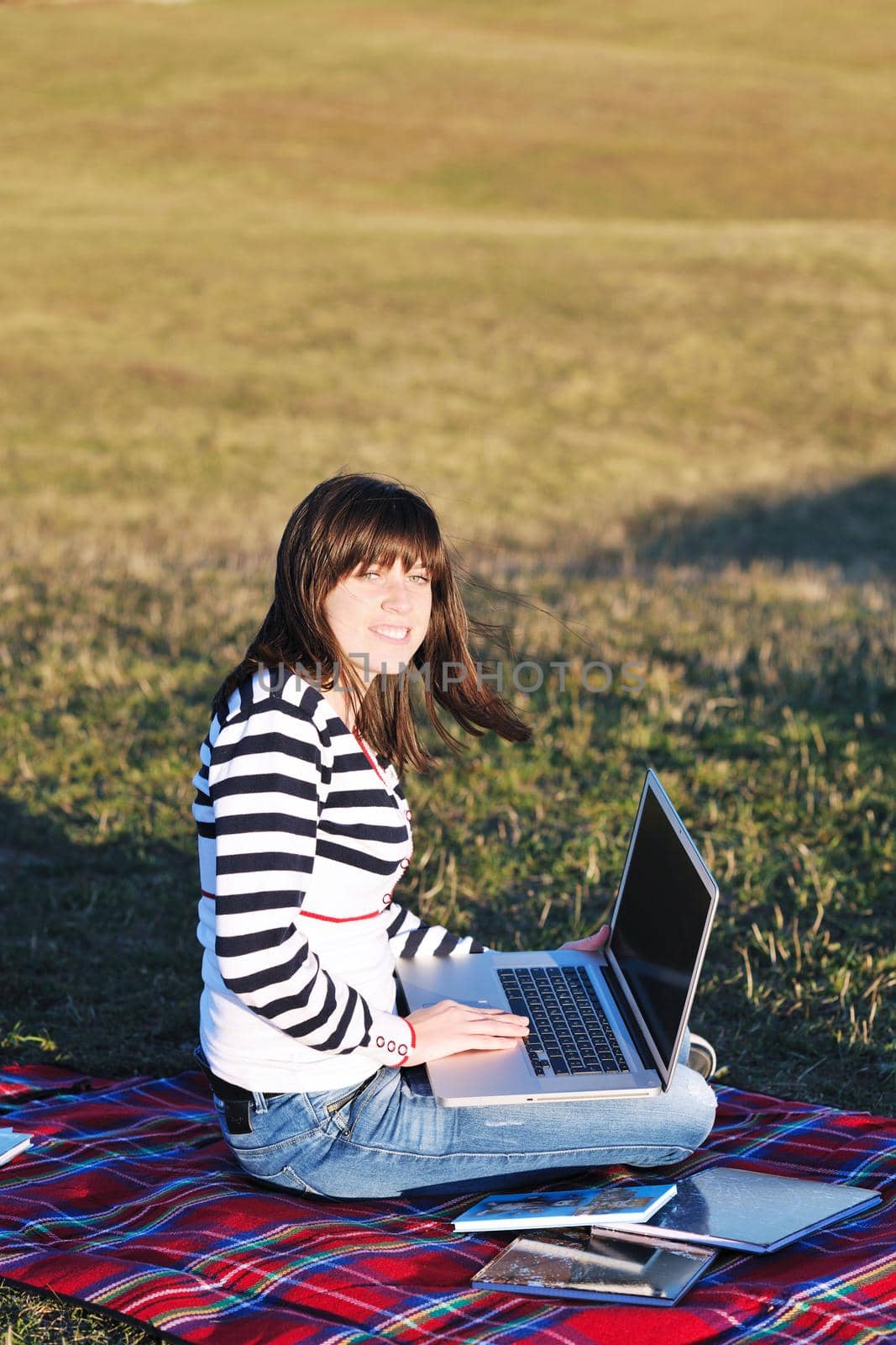 young teen girl work on laptop outdoor by dotshock