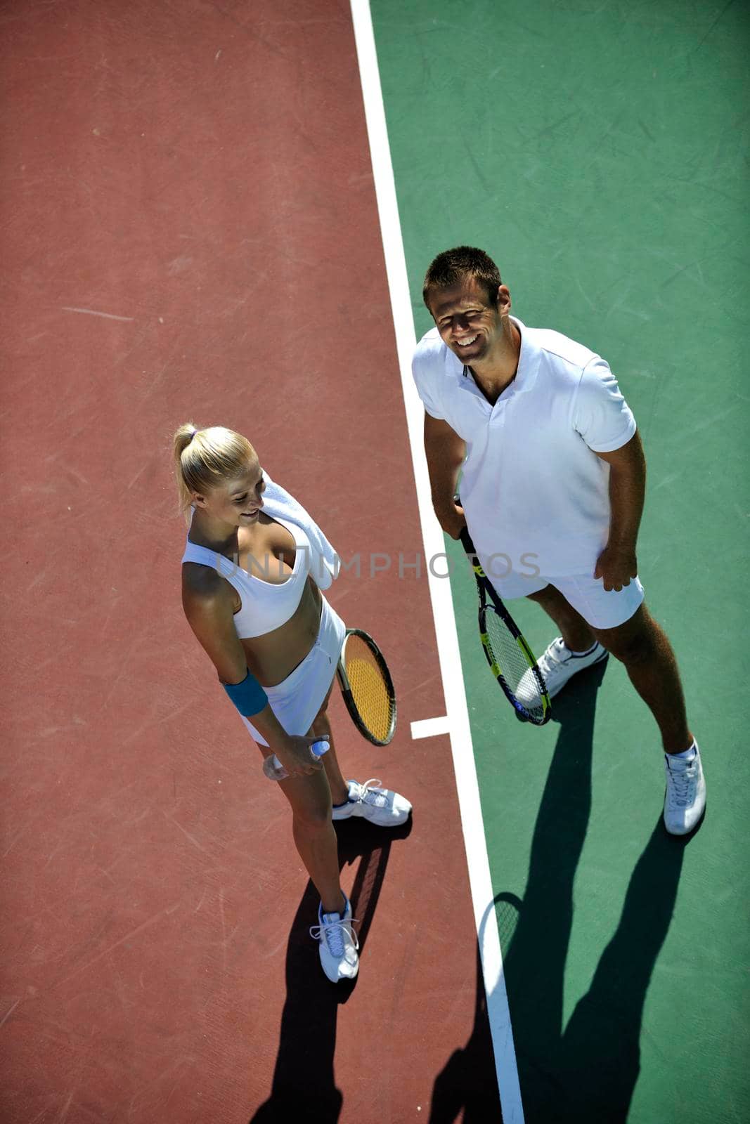 happy young couple play tennis game outdoor by dotshock